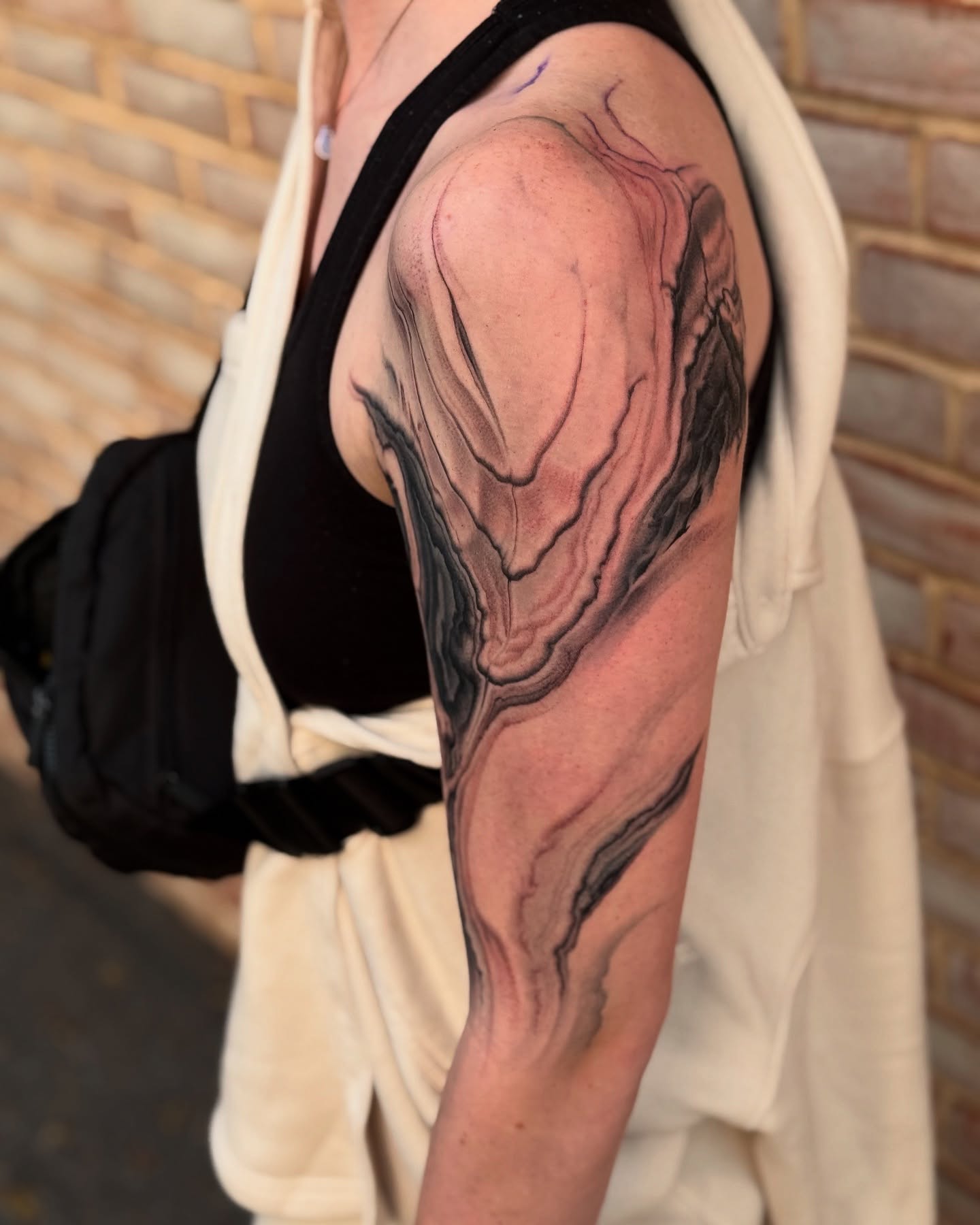 Abstract fluid black and grey tattoo on the shoulder by Jake Kirk