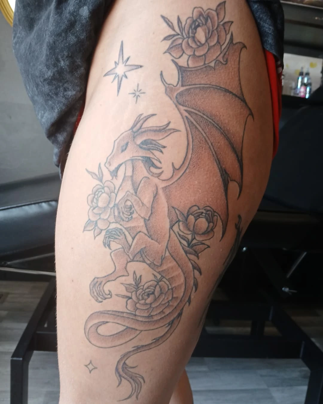 Dragon and flowers black and grey tattoo on the thigh by Cassieal Welch