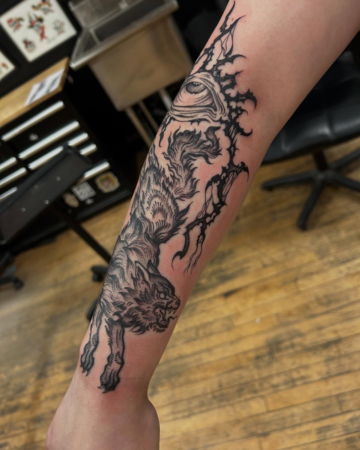 Wolf and eye black and grey tattoo on the forearm by Sam Perry, Denver, Colorado