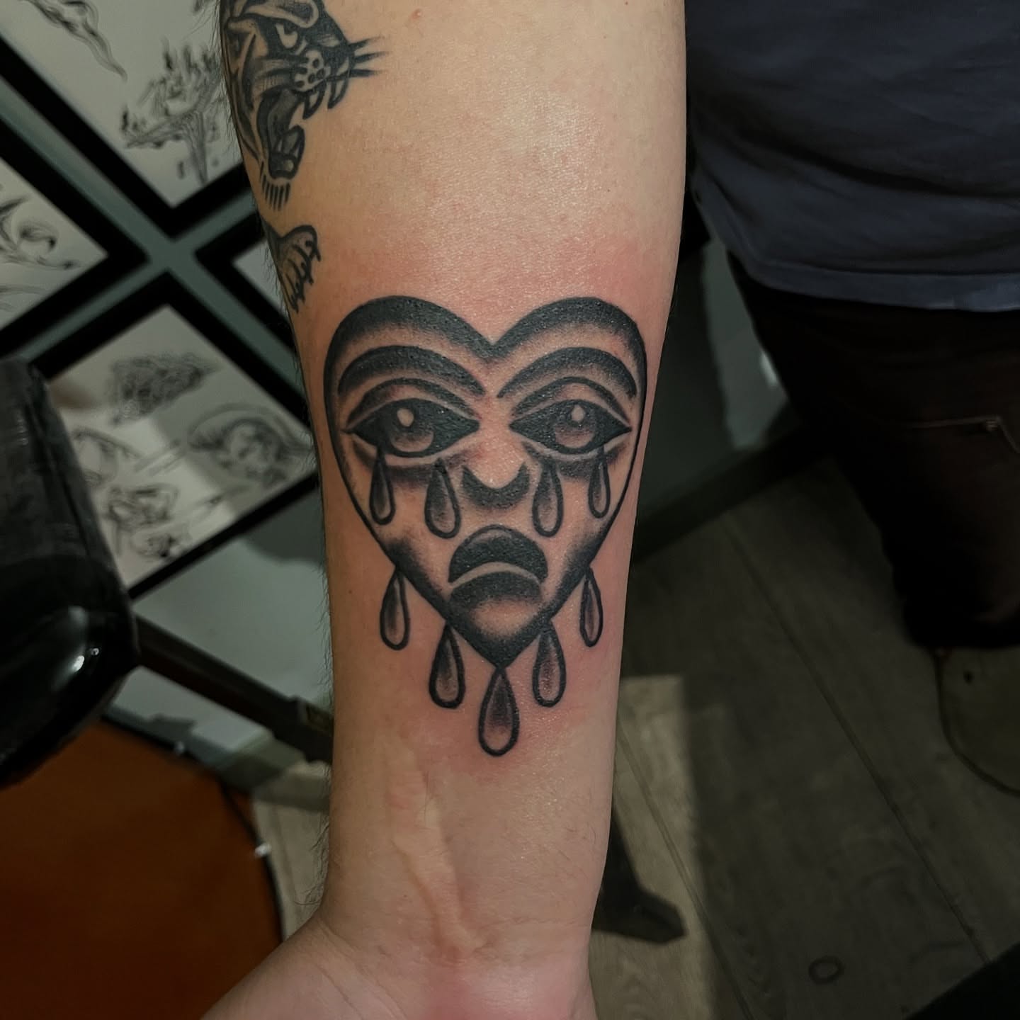 Tearful face black and grey tattoo on the forearm by Andrew Snowden