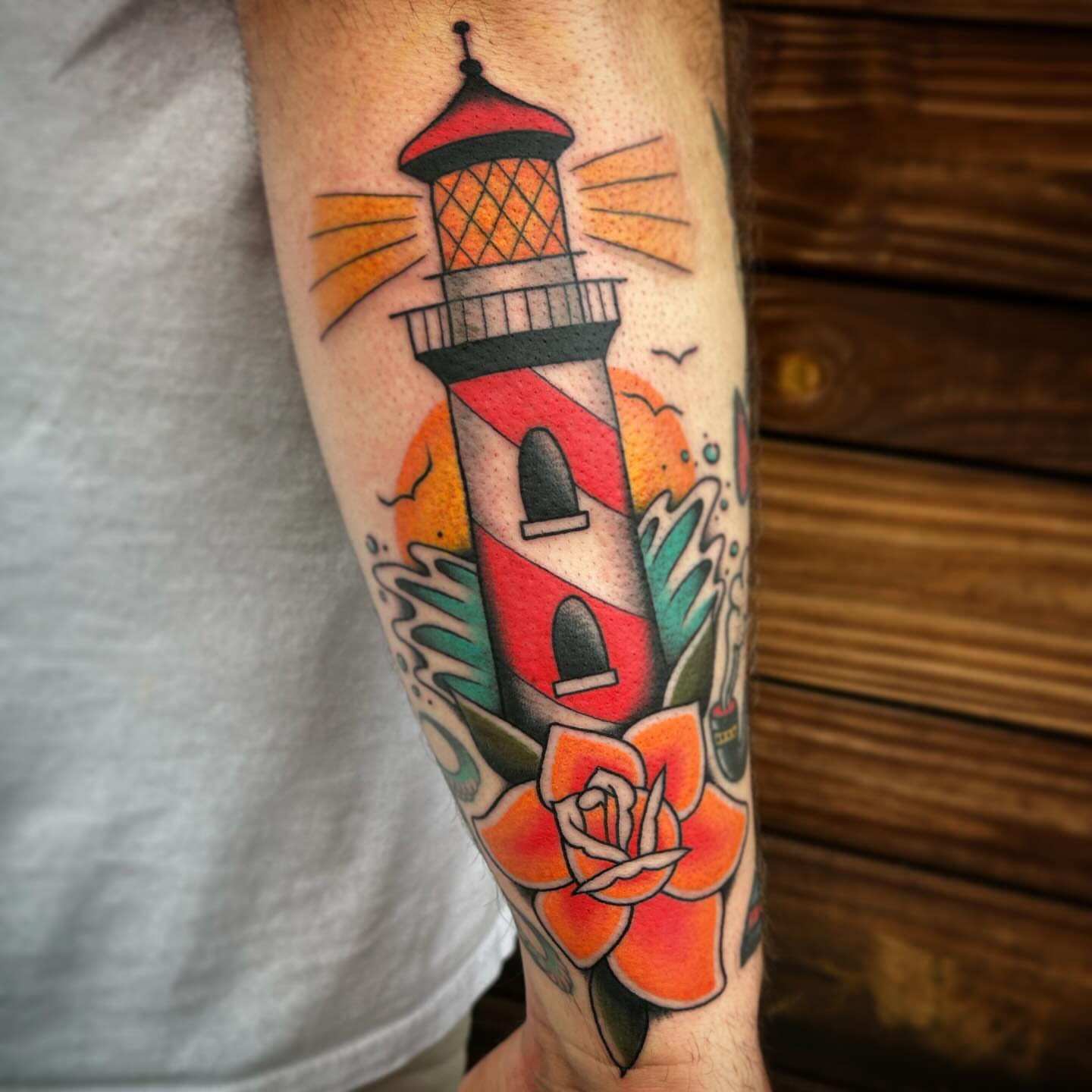 Lighthouse and flower American traditional tattoo on the forearm by Kayla Shoffner