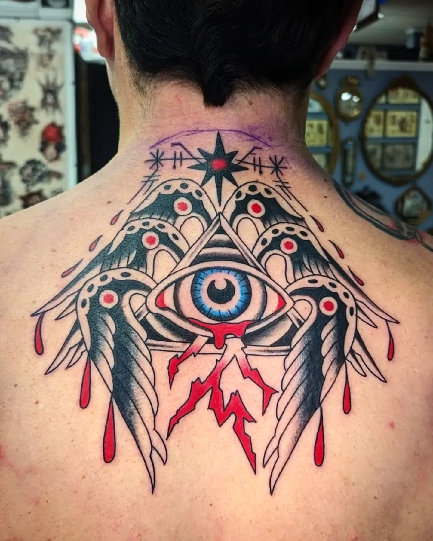 Eye with feathers geometric tattoo on the back by joseph palladino