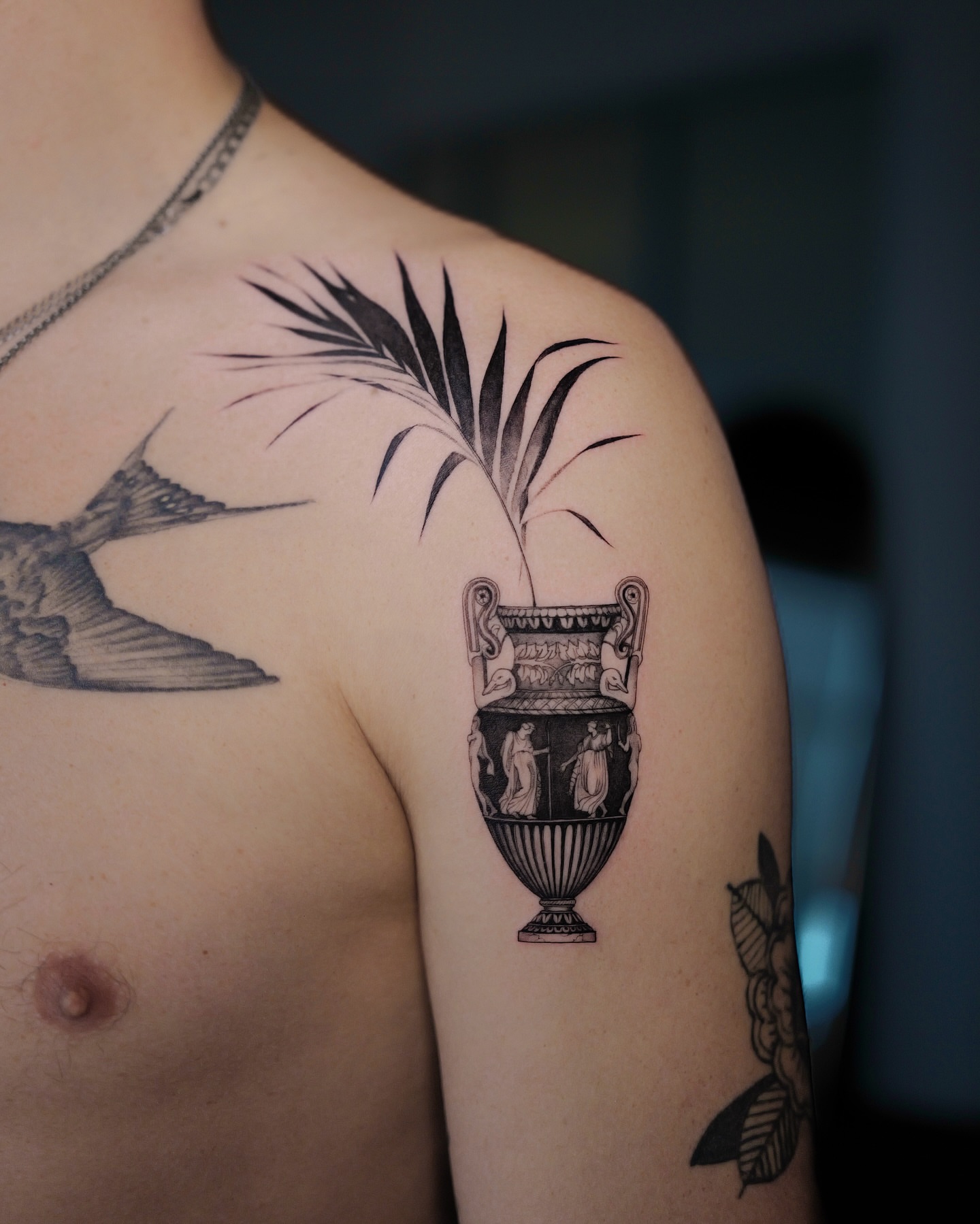 Ancient vase with palm frond black and grey tattoo on the shoulder by Tattoo Artist