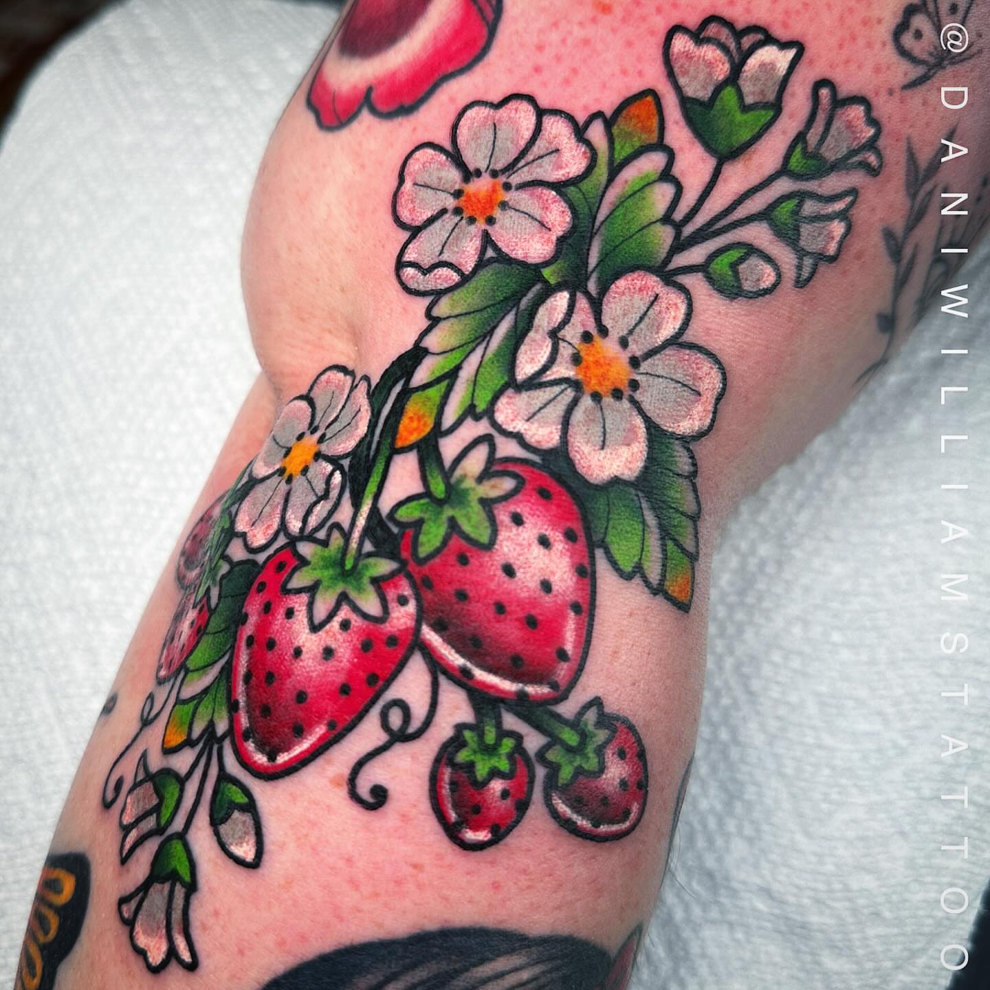 Strawberries and blossoms American traditional tattoo on the forearm by Dani Johnson