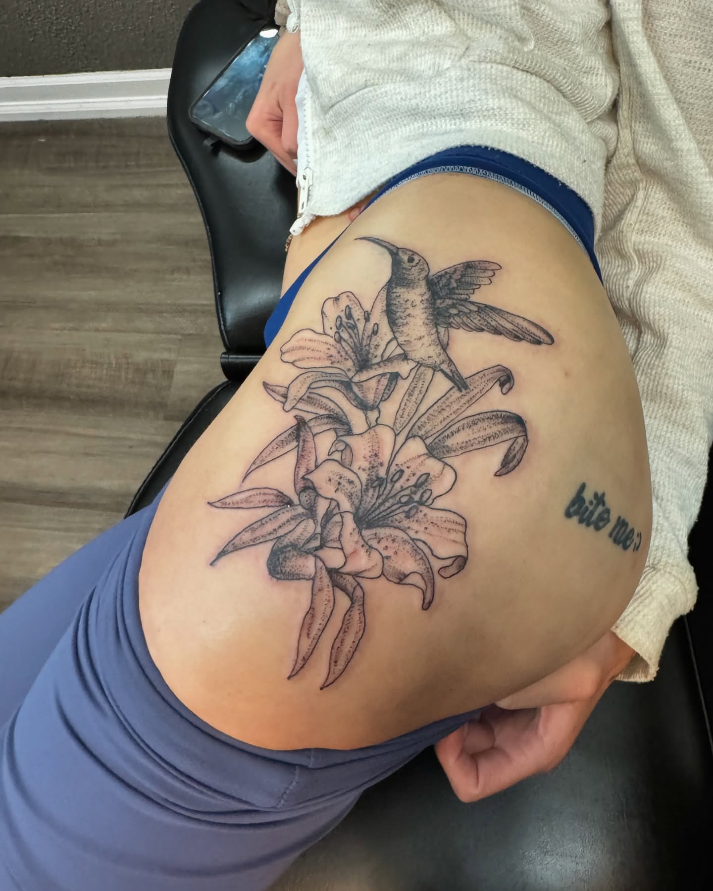 Lilies and hummingbird black and grey tattoo on the thigh by Lexy