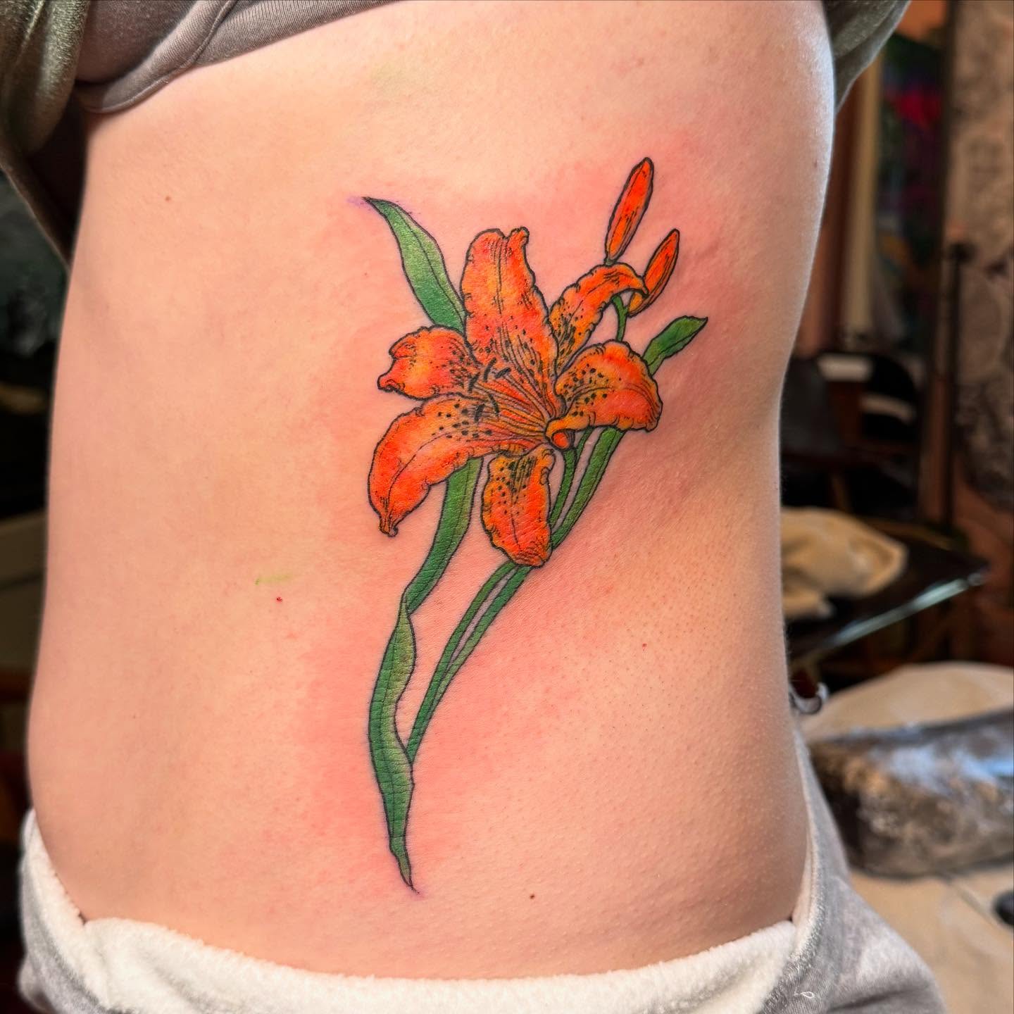 Orange lily realism tattoo on the ribs by Rebeka Chase [Sobodacha]