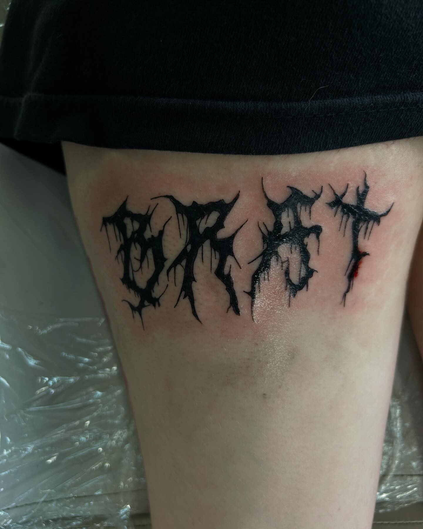 Lettering black and grey tattoo on the thigh by Haley Winfree