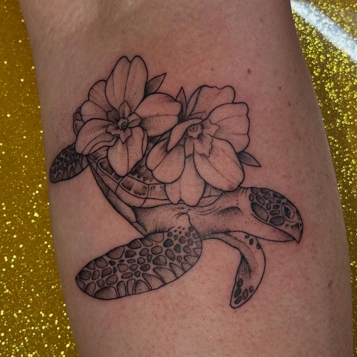 Sea turtle with flowers black and grey tattoo on the forearm by Abigail Townsend