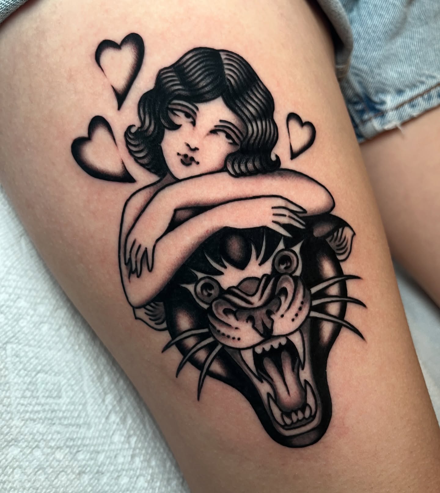 Woman hugging tiger American traditional tattoo on the thigh by kate