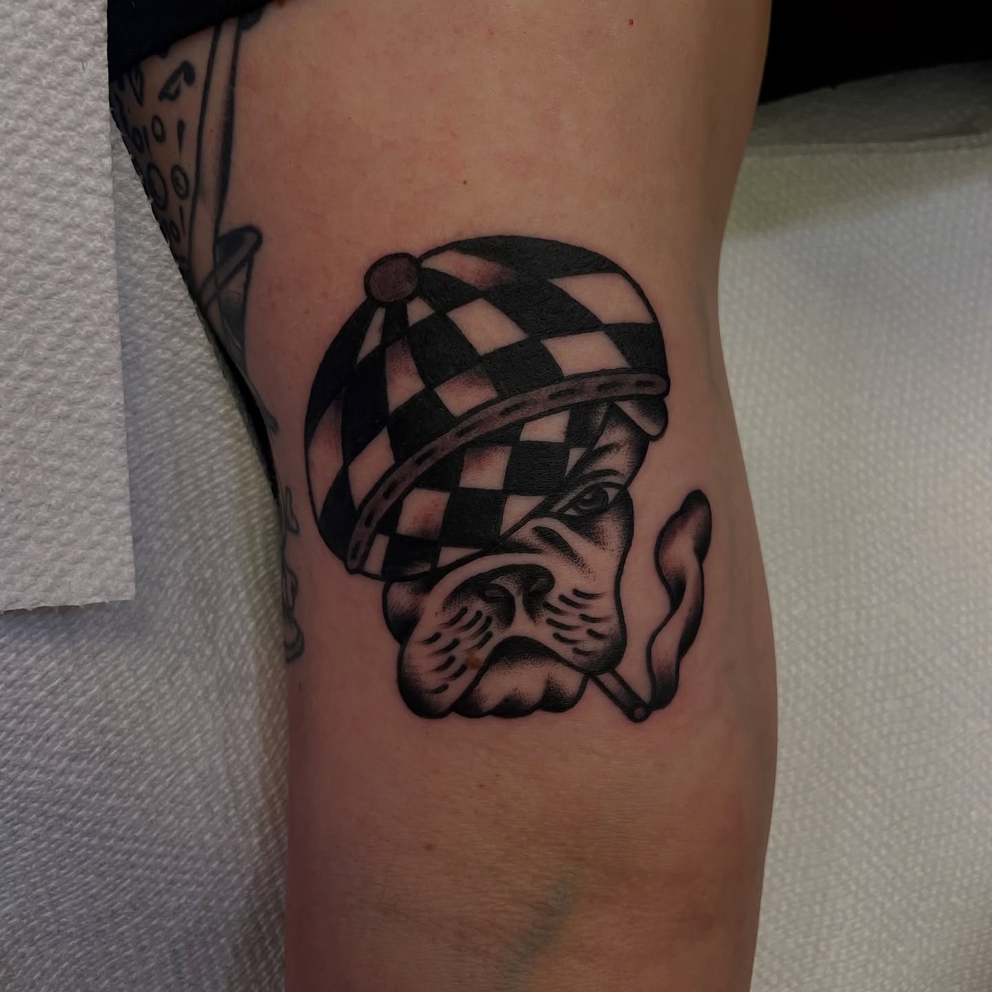 Bulldog wearing checkered hat black and grey tattoo on the forearm by Texas Jonah