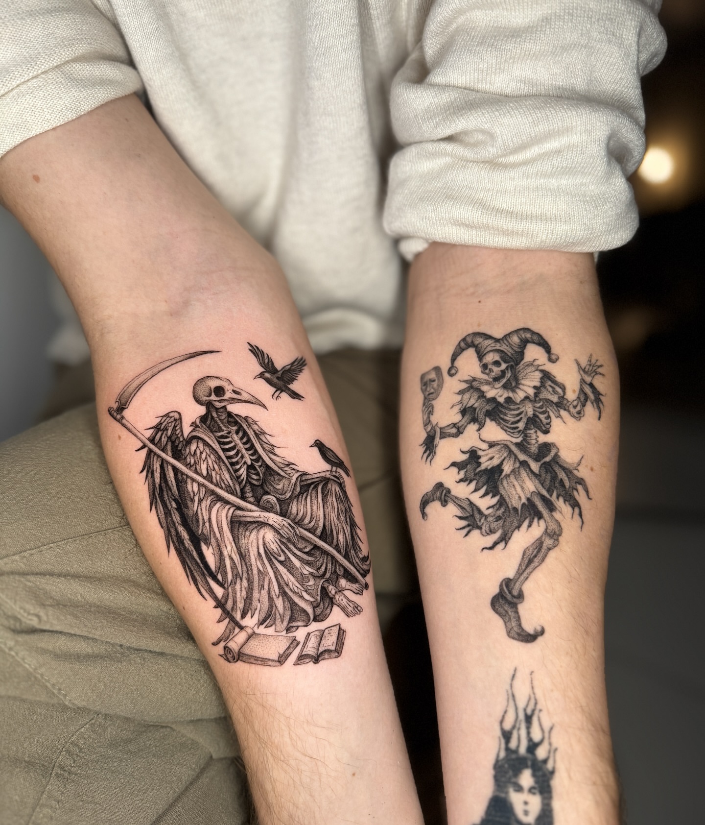 Grim reaper and jester realism tattoo on the forearm by Cybersigilism & Fineline Blackwork