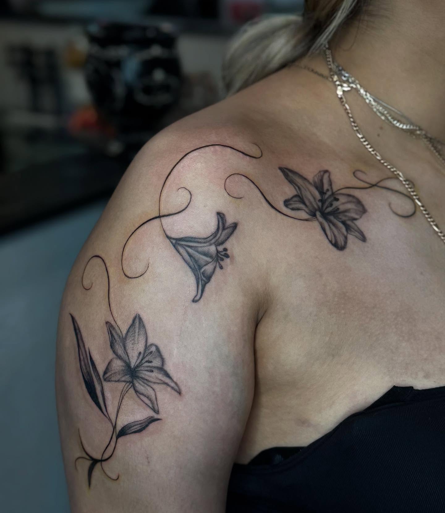 Lilies black and grey tattoo on the shoulder by Alexa Camacho