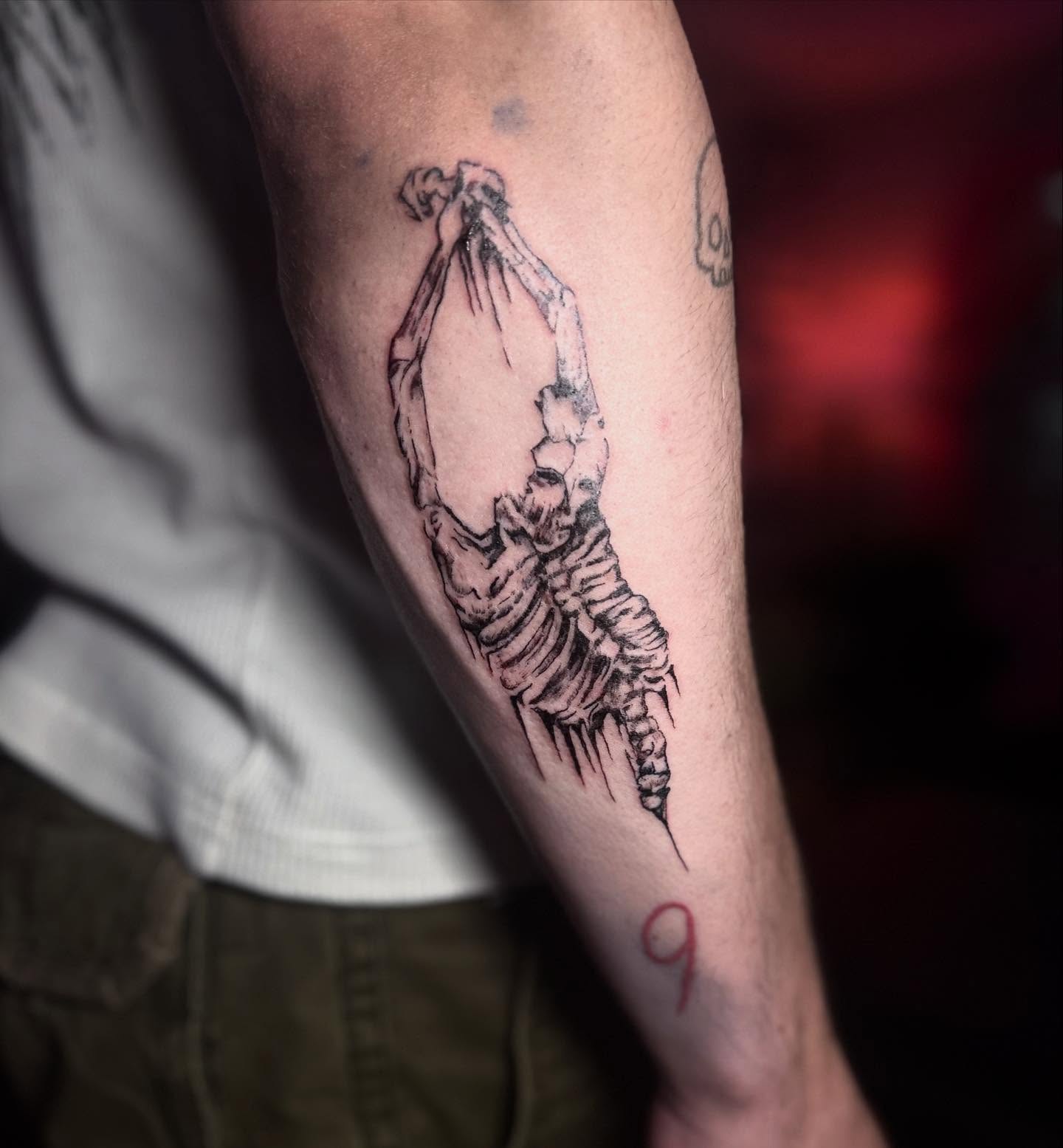 Skeleton hanging black and grey tattoo on the forearm by Cullen-Lee