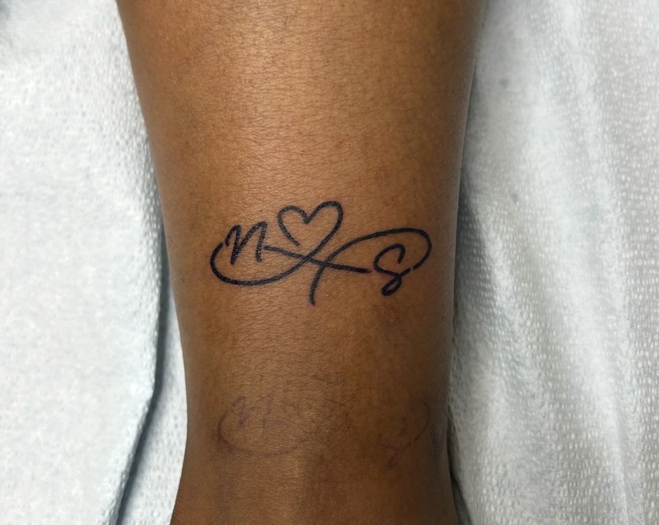 Infinity symbol with heart lettering script tattoo on the forearm by Elizabeth Niederkorn