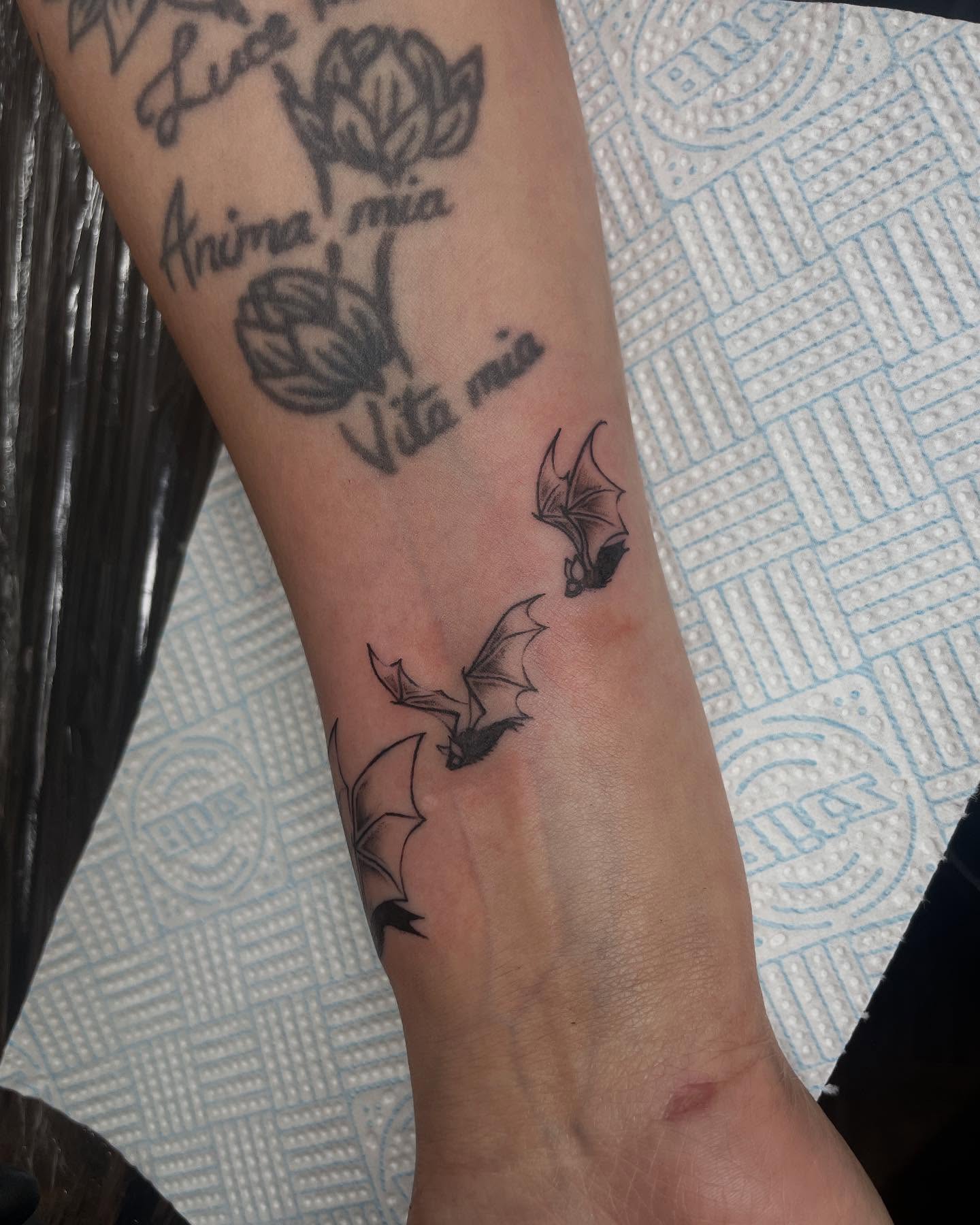 Bats and lotus black and grey tattoo on the forearm by Grace derby tattooist, Derby