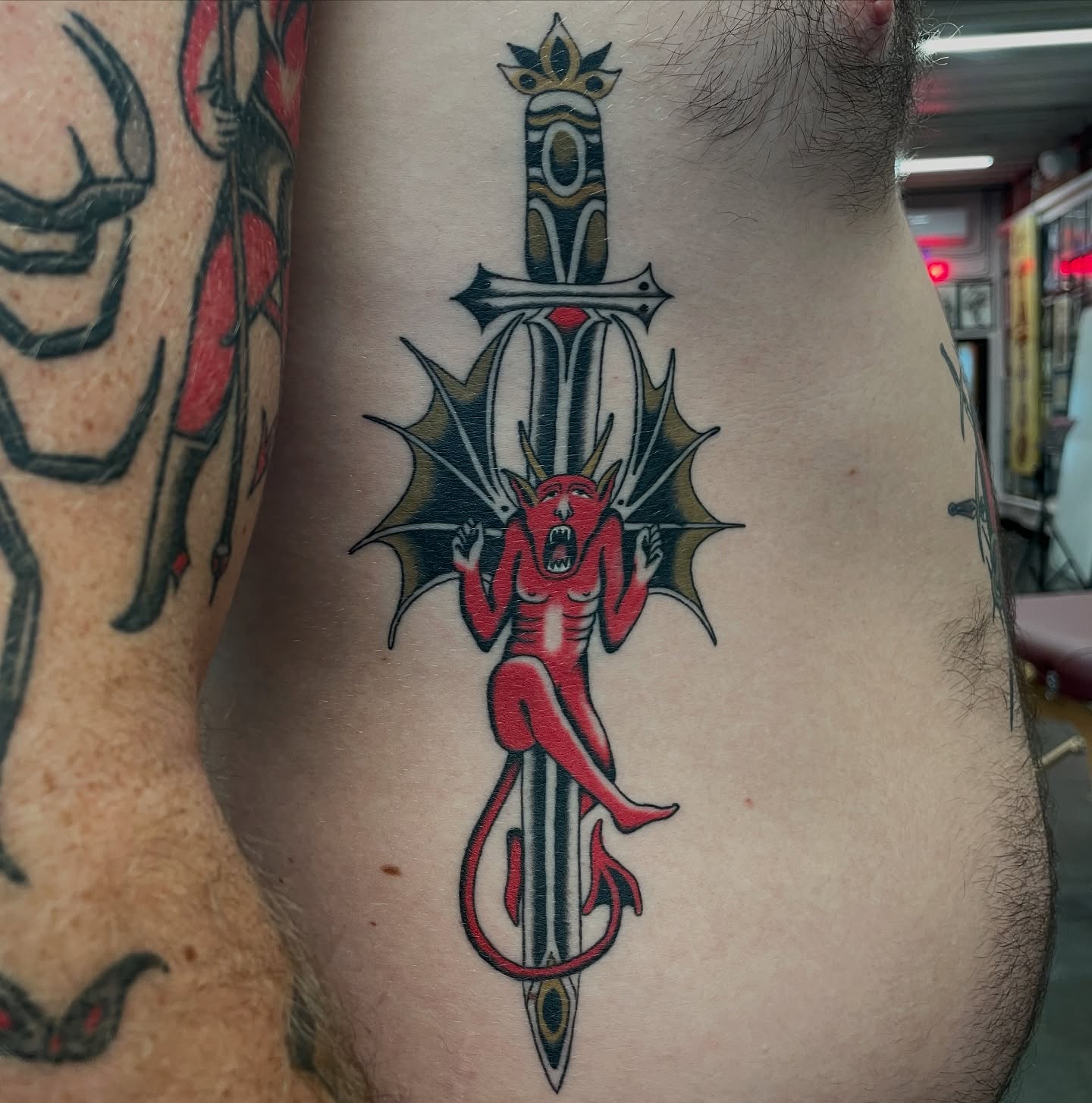 Demon on sword American traditional tattoo on the ribs by Niko Mulhearn