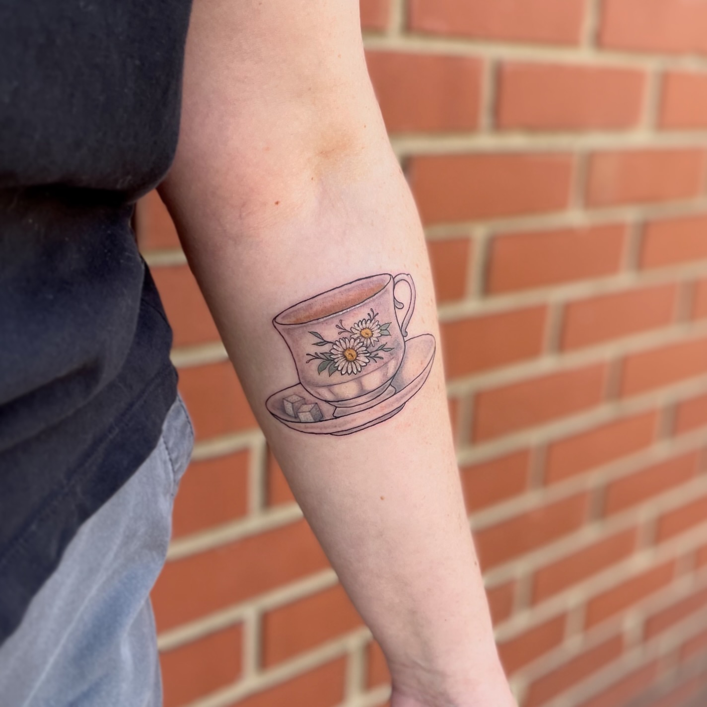 Teacup and flowers realism tattoo on the forearm by Liv