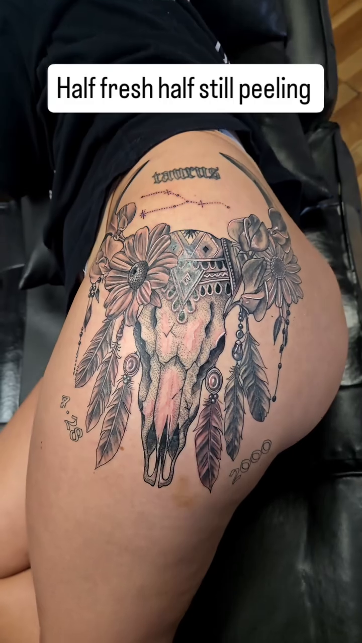 Skull with flowers and feathers realism tattoo by Camuel Whaley