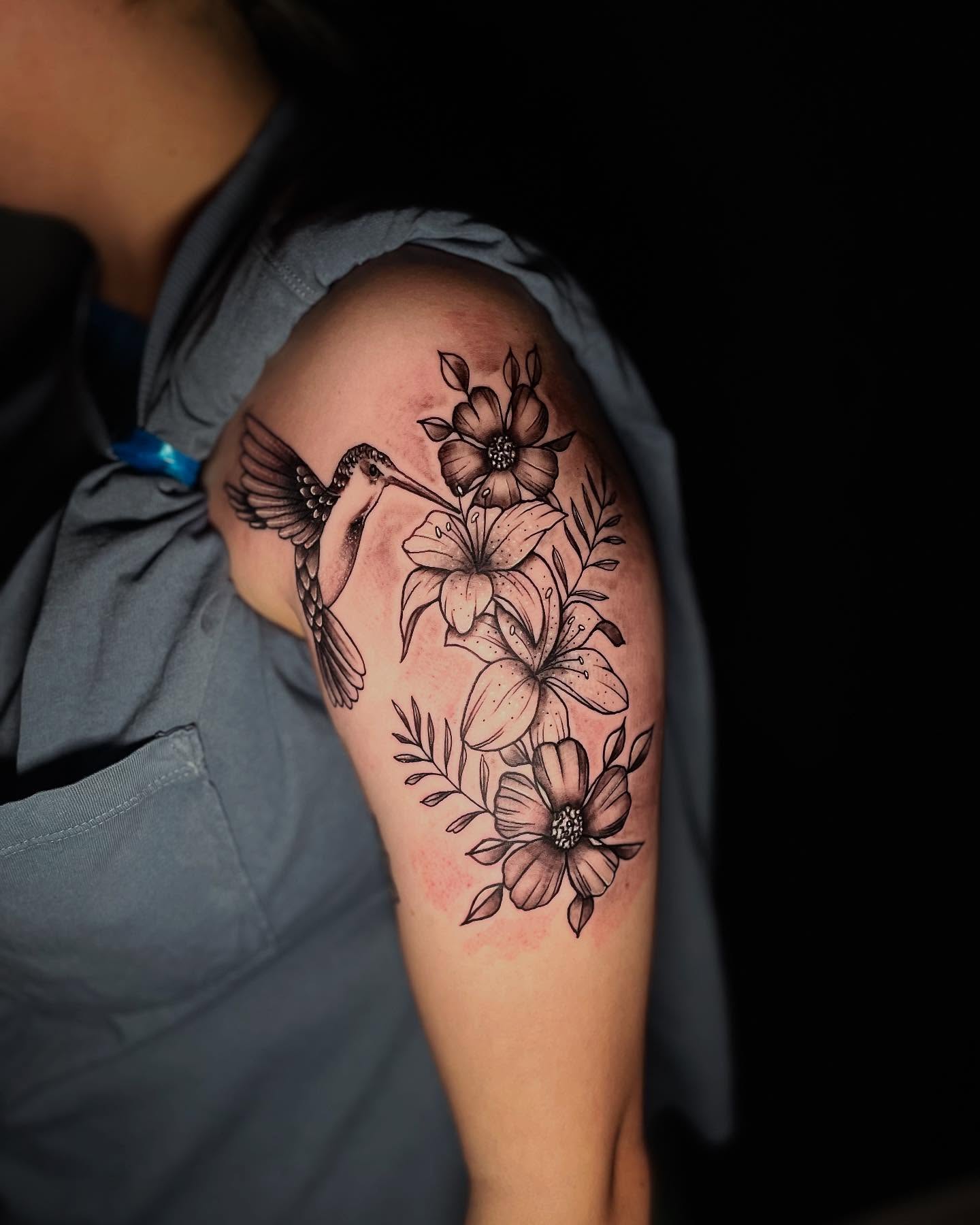 Hummingbird and flowers black and grey tattoo on the shoulder by Nicholas A. Estes-Davis