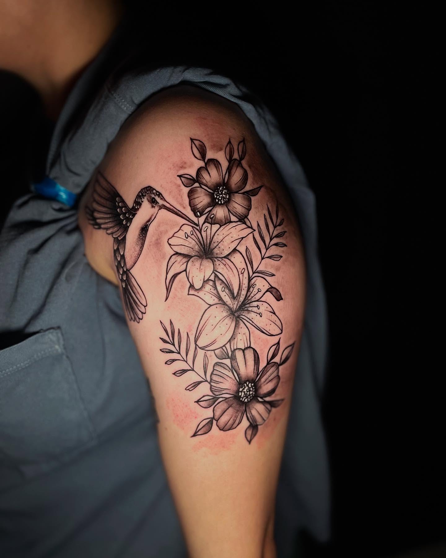 Hummingbird and flowers black and grey tattoo on the shoulder by Nicholas A. Estes-Davis