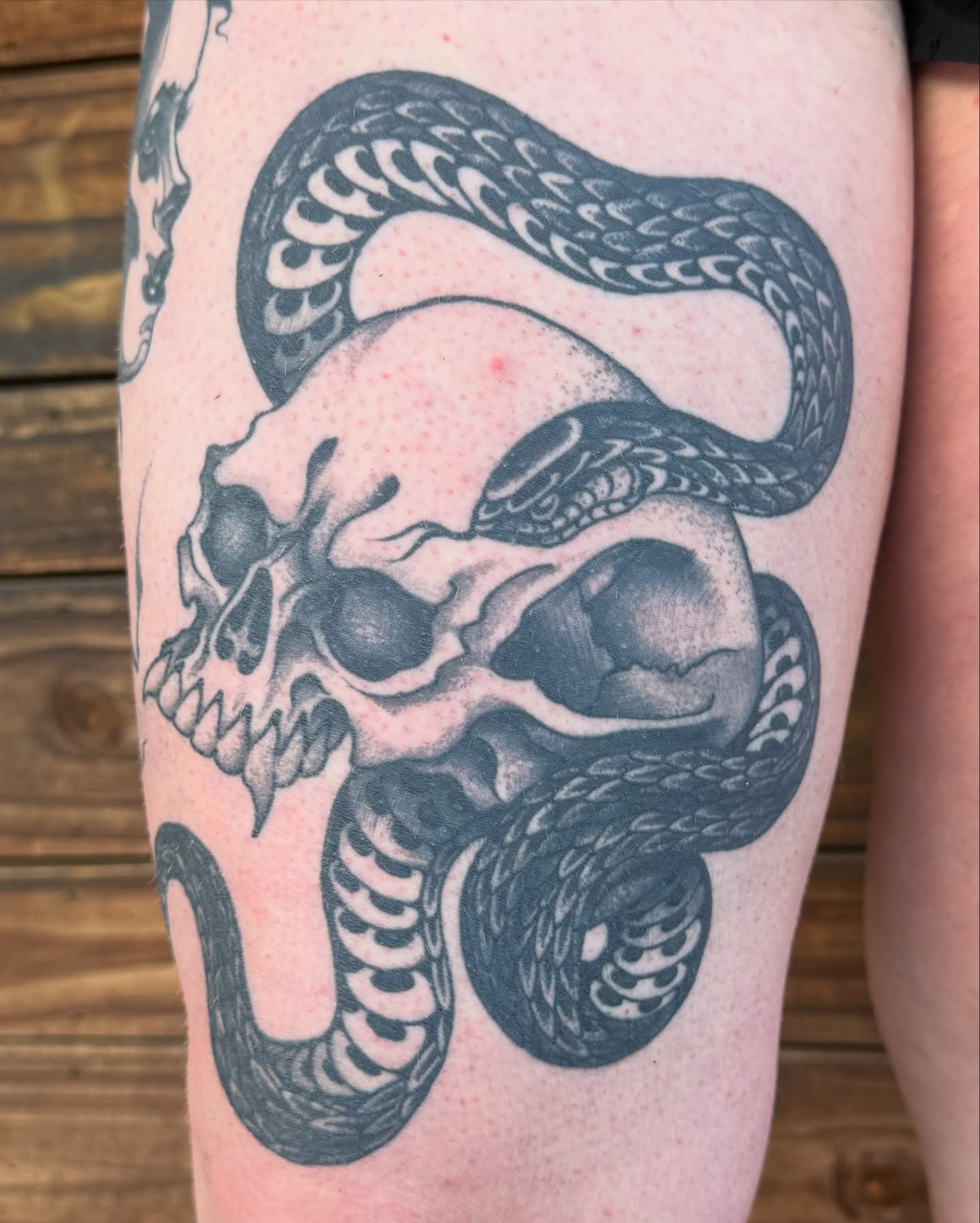 Skull and snake black and grey tattoo on the thigh by Scott Kulikowski