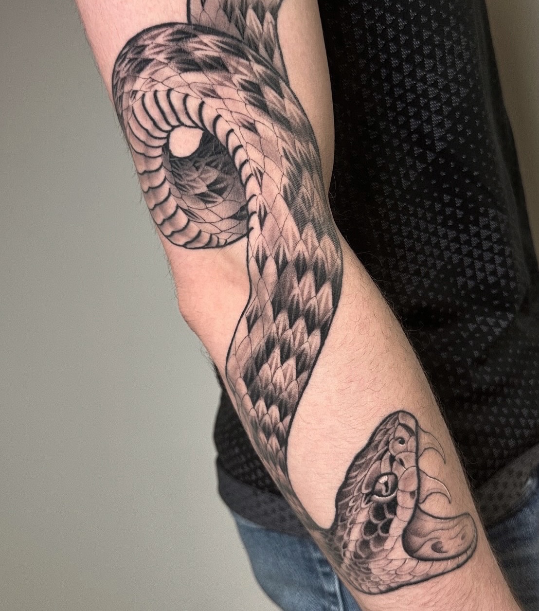 Snake black and grey tattoo on the forearm by Patrick Whiting