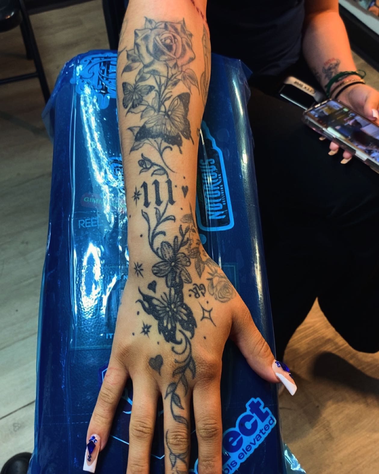 Floral and butterfly design black and grey tattoo on the forearm by Tattsruru