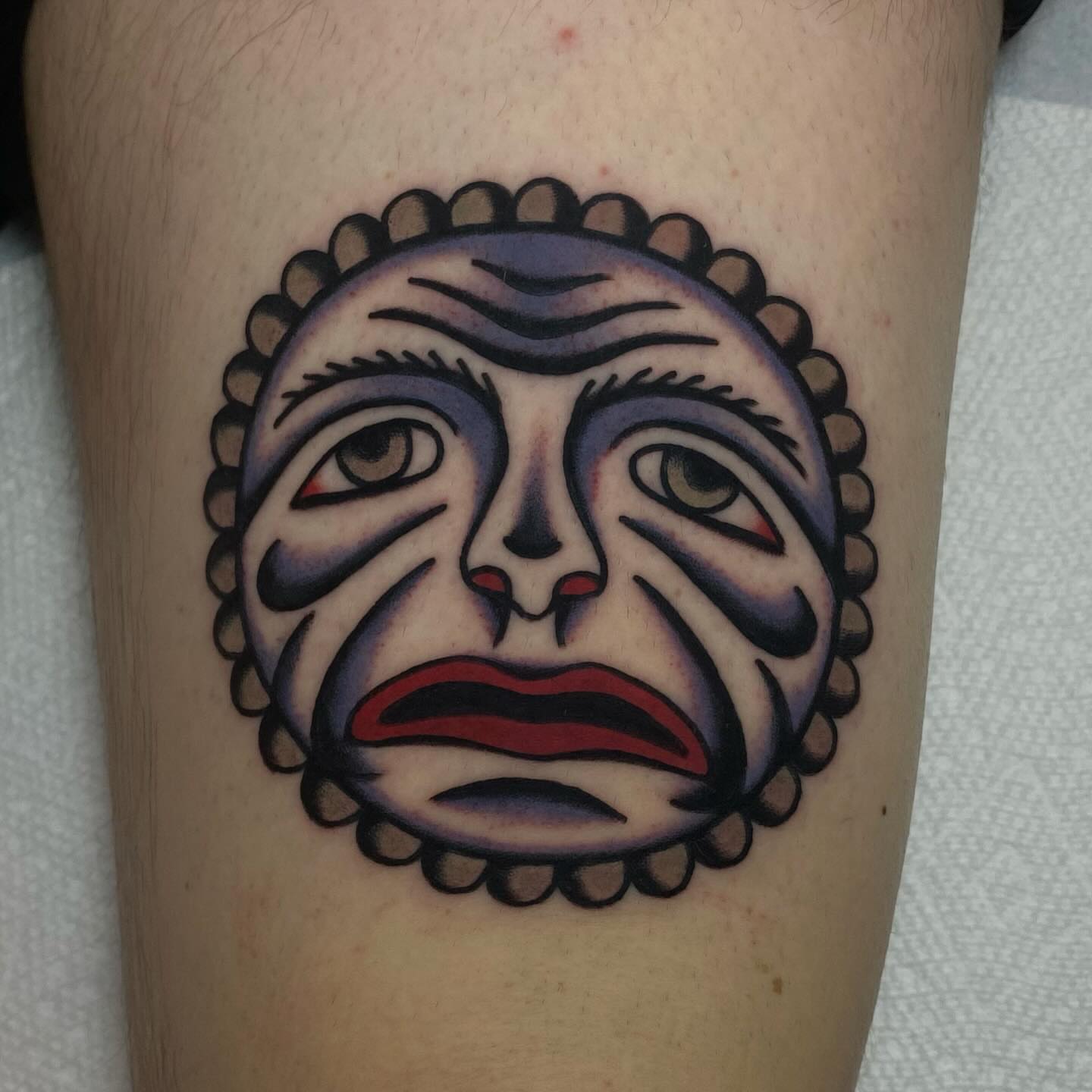 Sad mask American traditional tattoo on the forearm by Erin Chambers