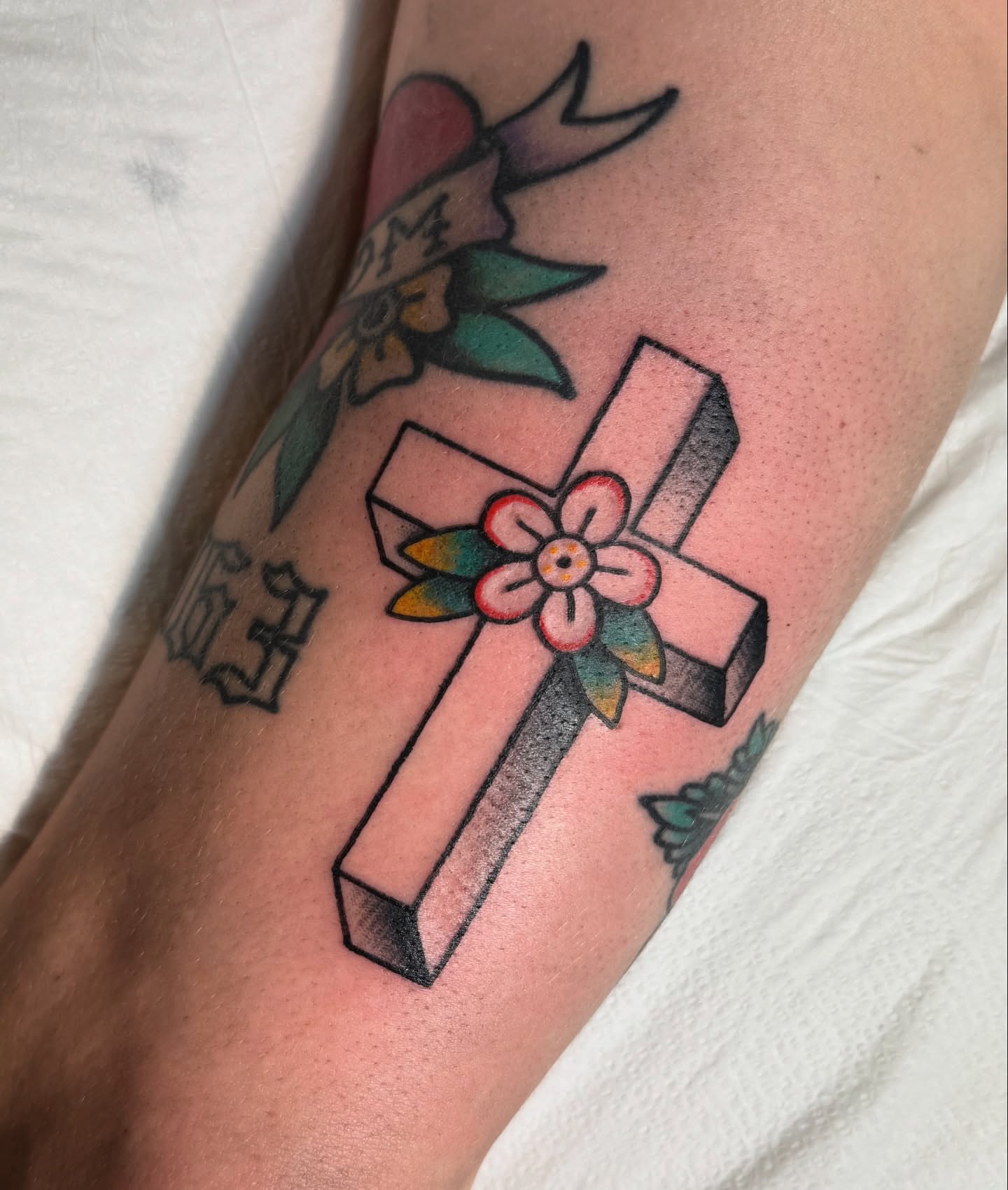 Cross with flower American traditional tattoo on the forearm by Mazie