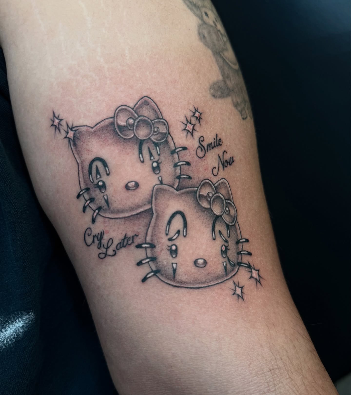 Hello Kitty black and grey tattoo on the forearm by dinah