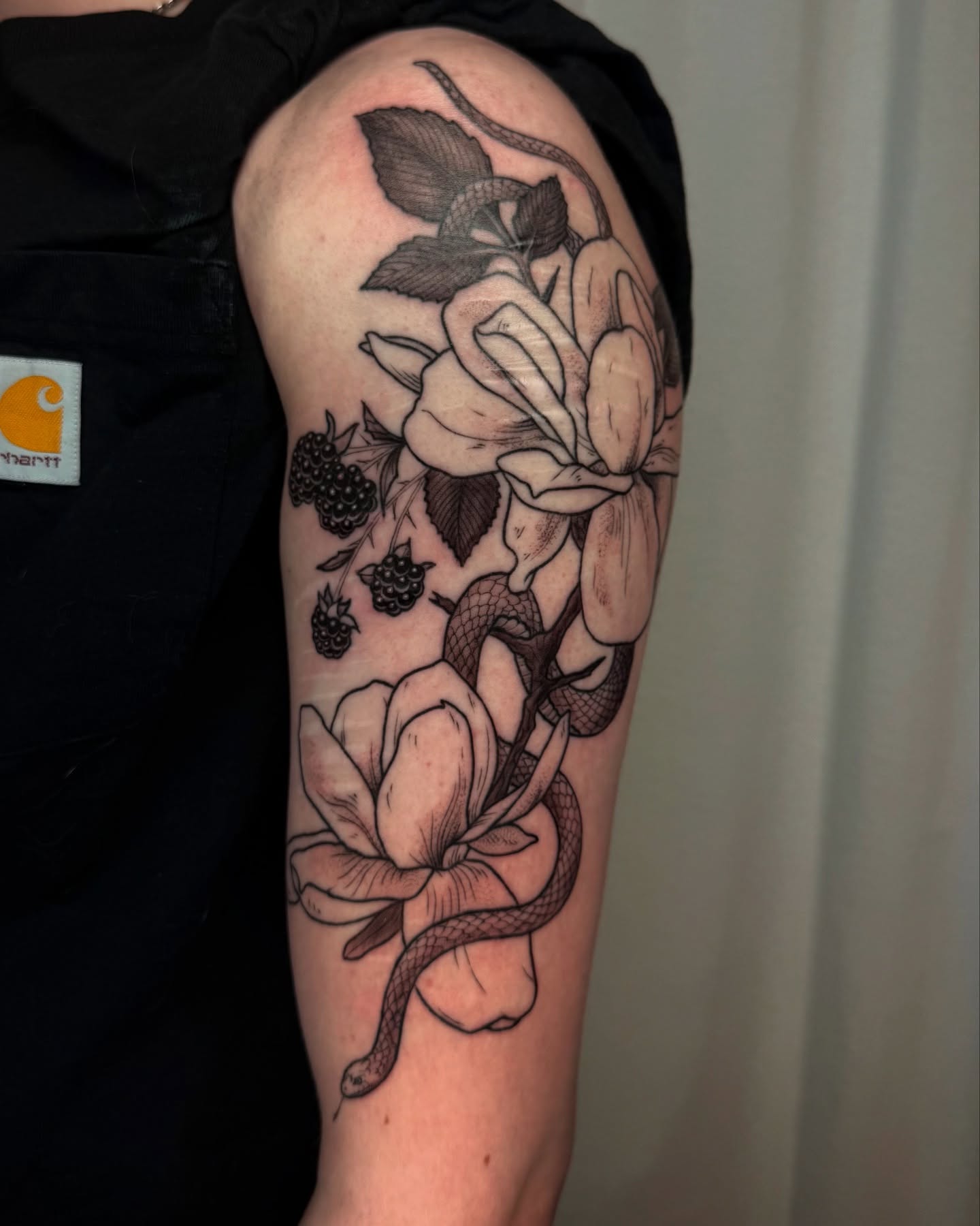 Snake and magnolia realism tattoo on the forearm by Cooper