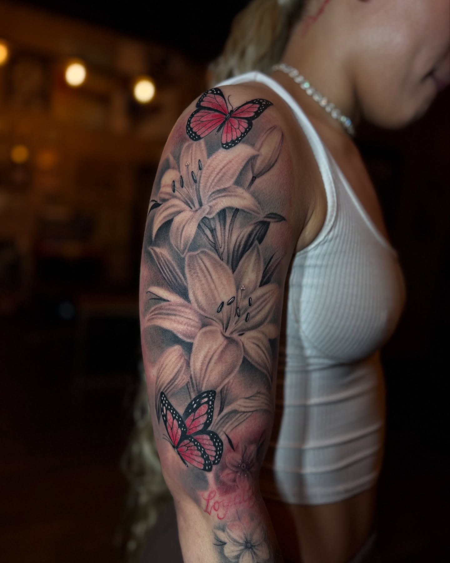 Lilies and butterflies realism tattoo on the upper arm by Jevon Glasco Tattoos