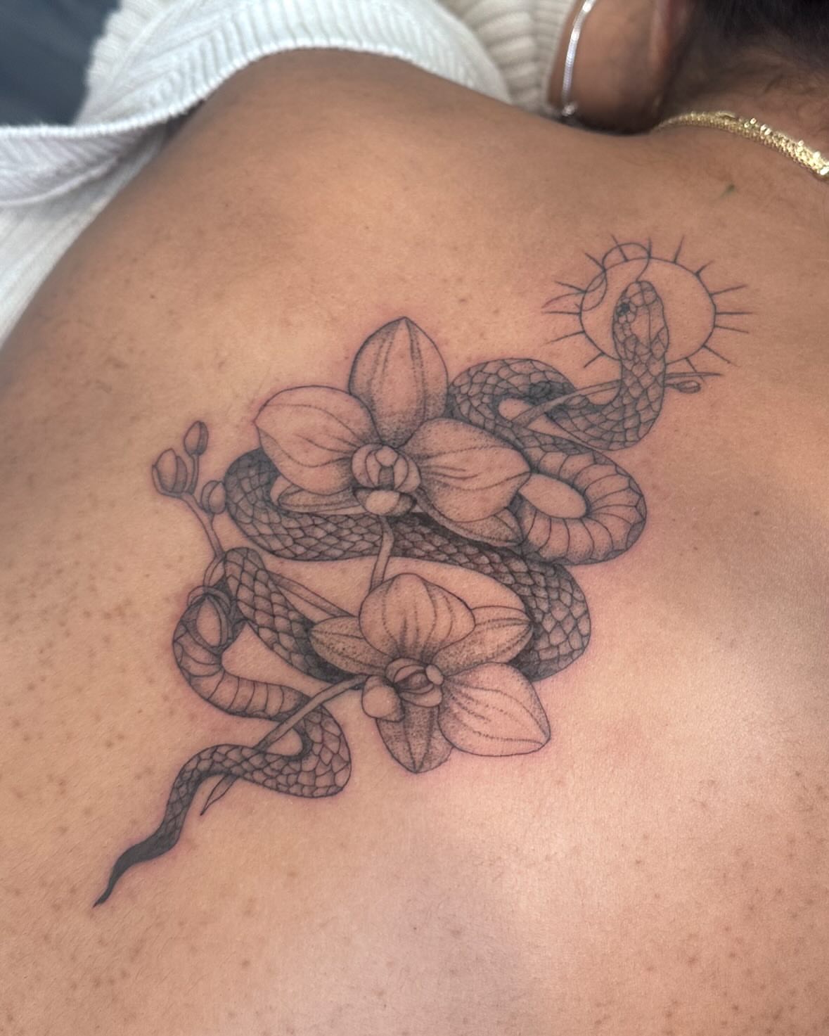 Snake and orchids black and grey tattoo on the shoulder by Bell