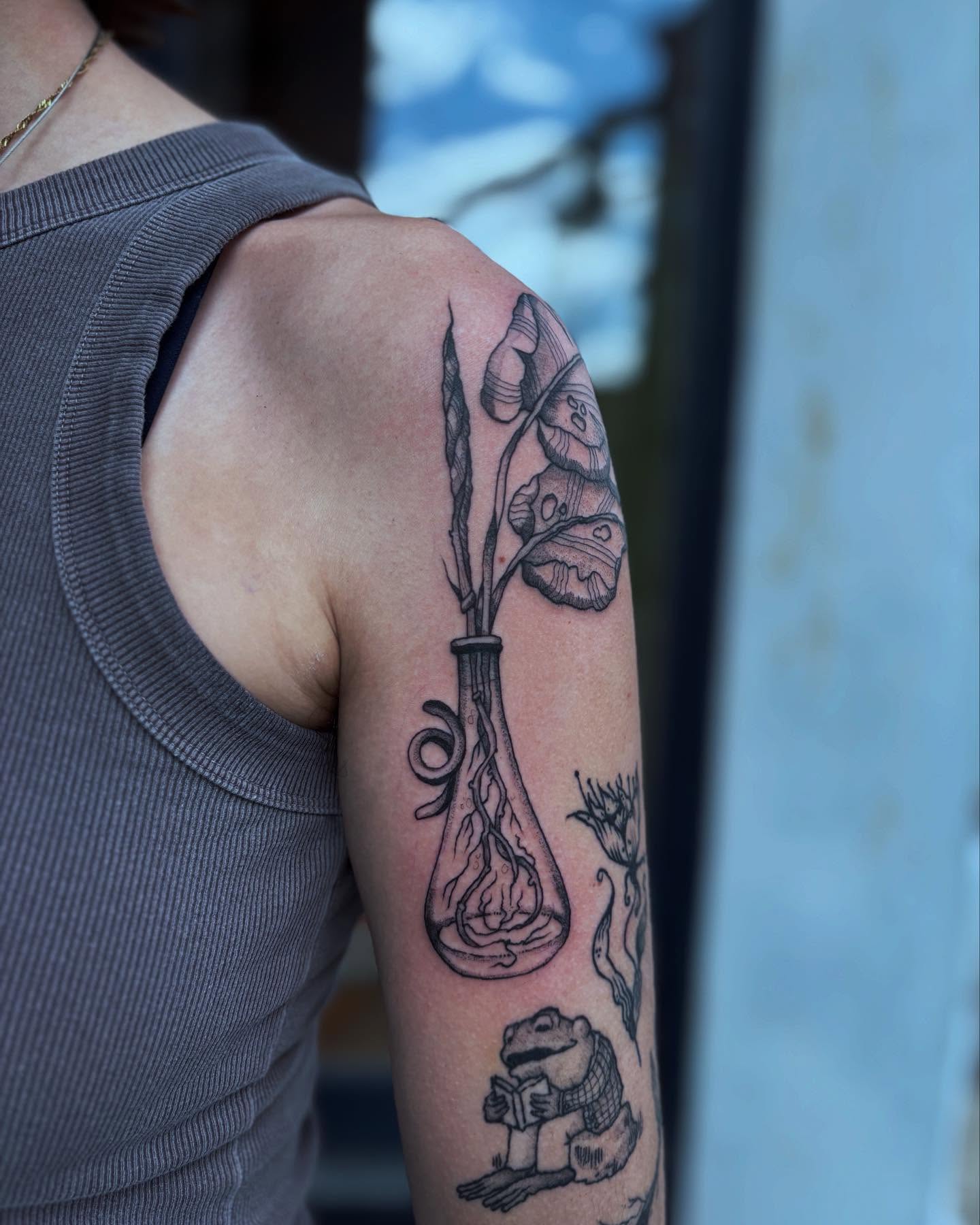 Vase with flowers and frog realism tattoo on the upper arm by kris noble floyd
