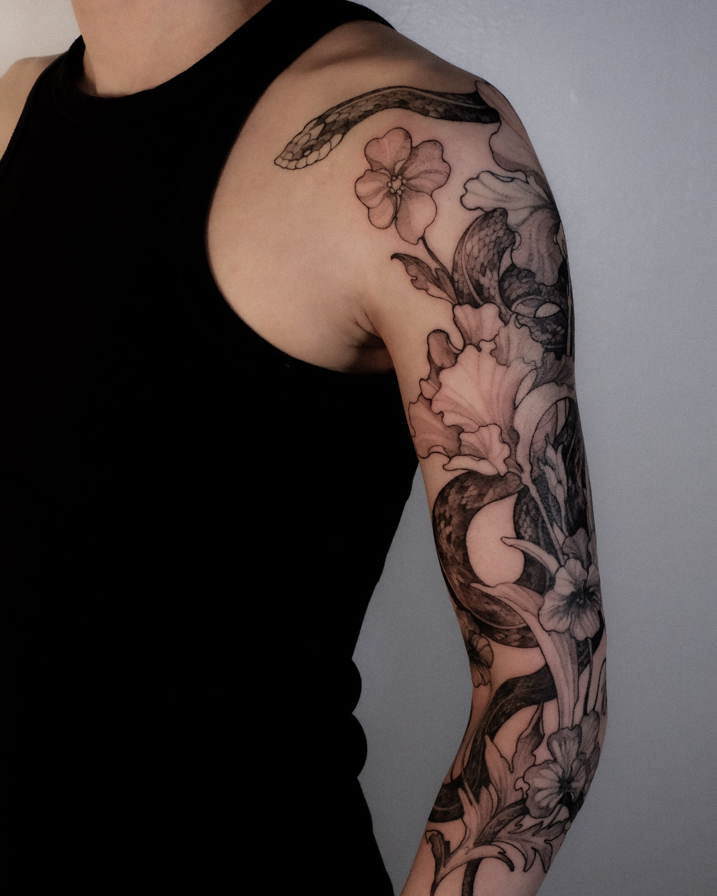 Floral and snake realism tattoo on the upper arm by Alena Zozulenko