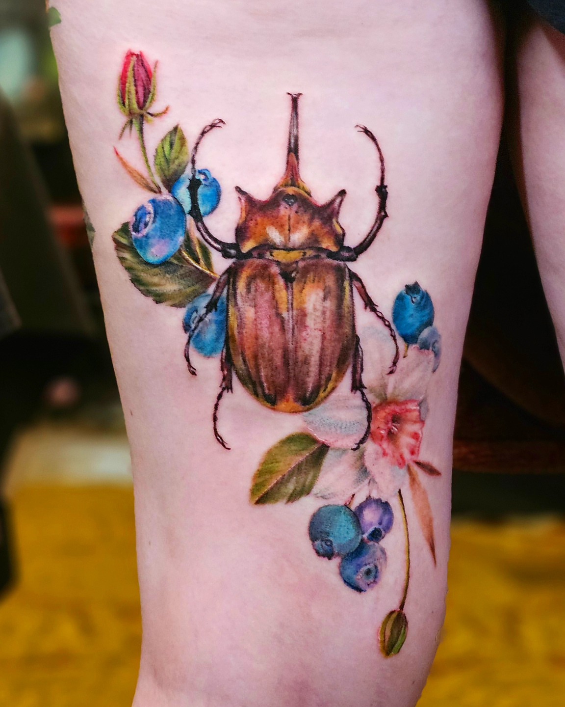 Beetle with berries realism tattoo on the forearm by Madelynne