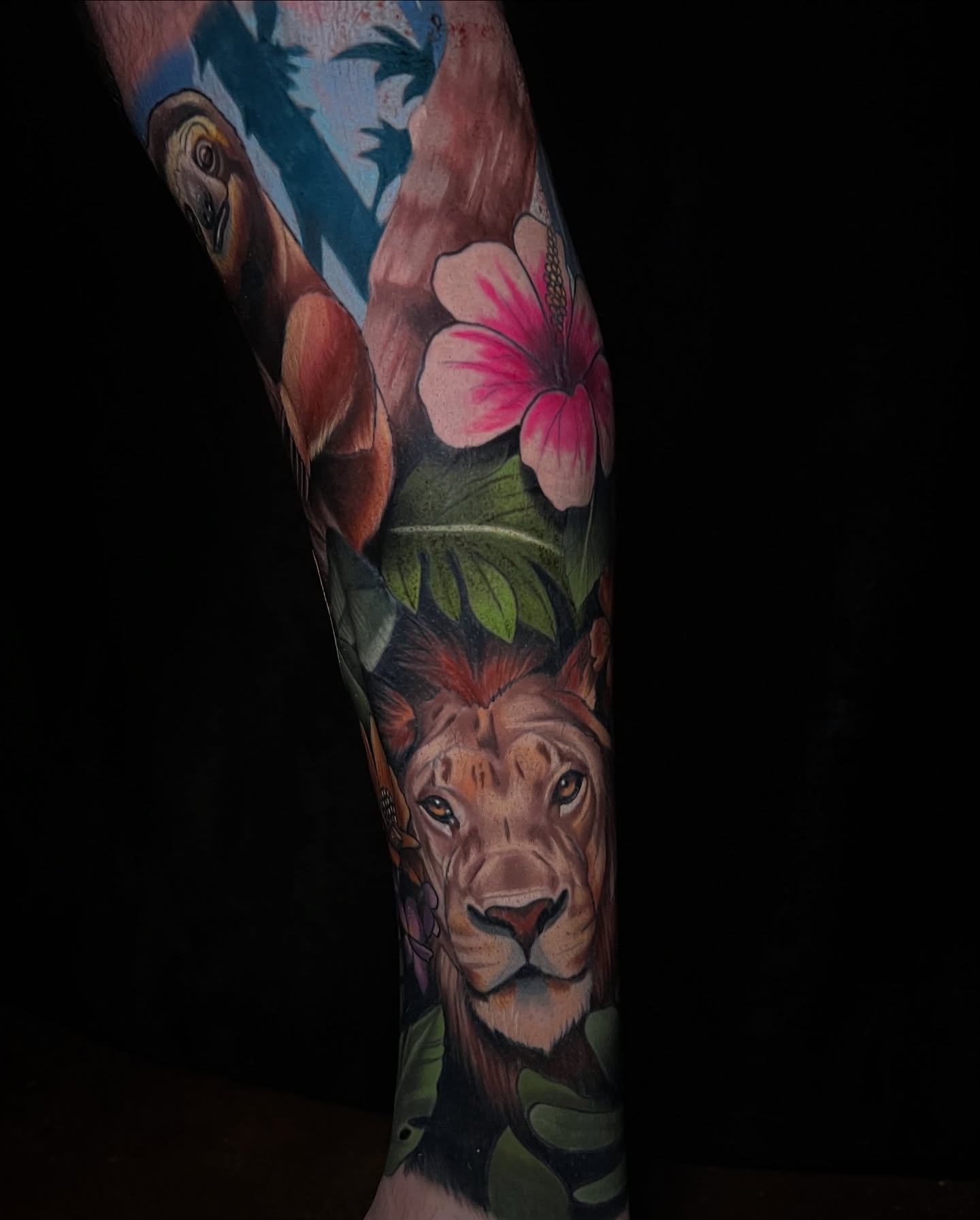 Lion and flowers realism tattoo on the forearm by Emily Walker