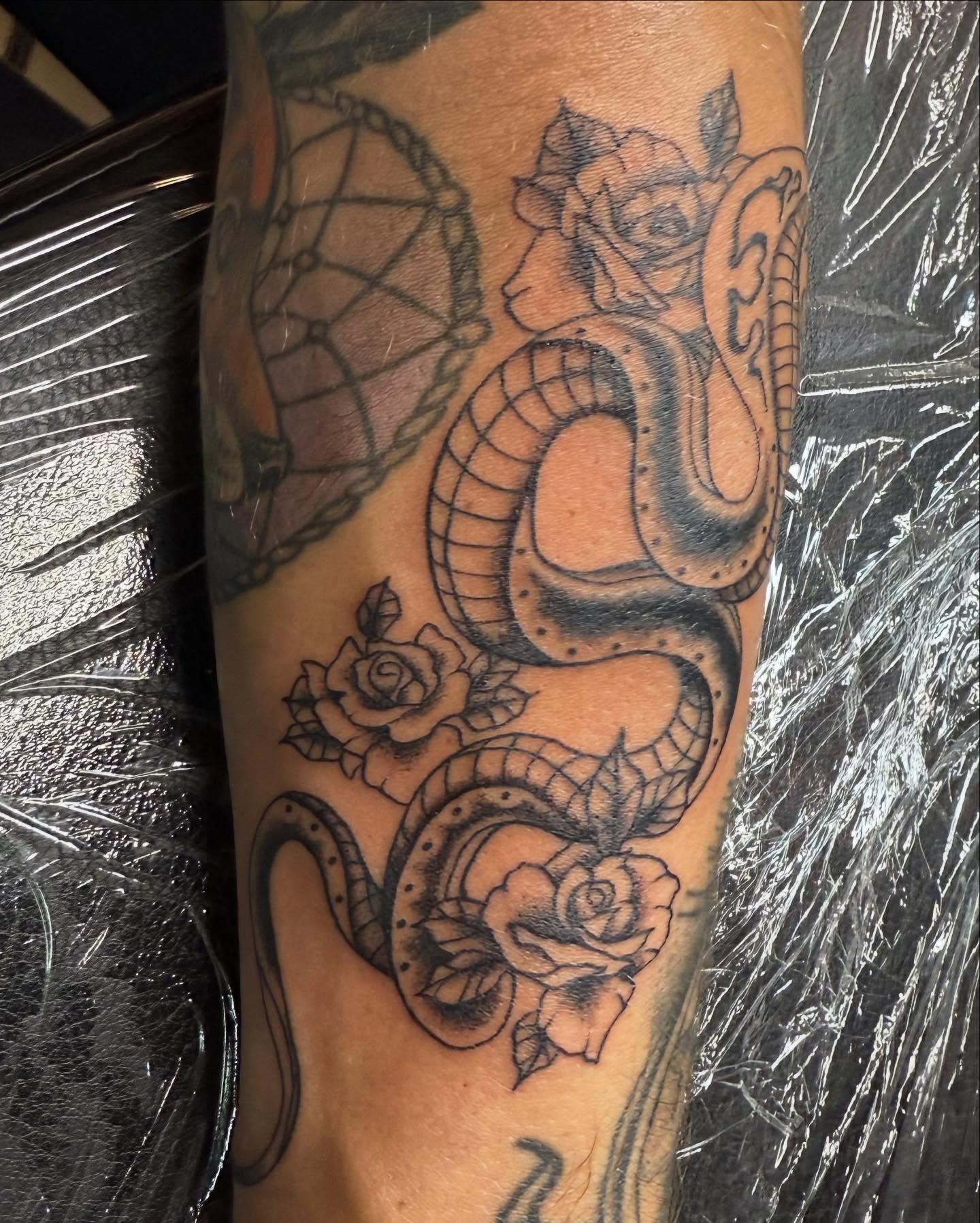 Snake and roses black and grey tattoo on the forearm by Hunter Beyer