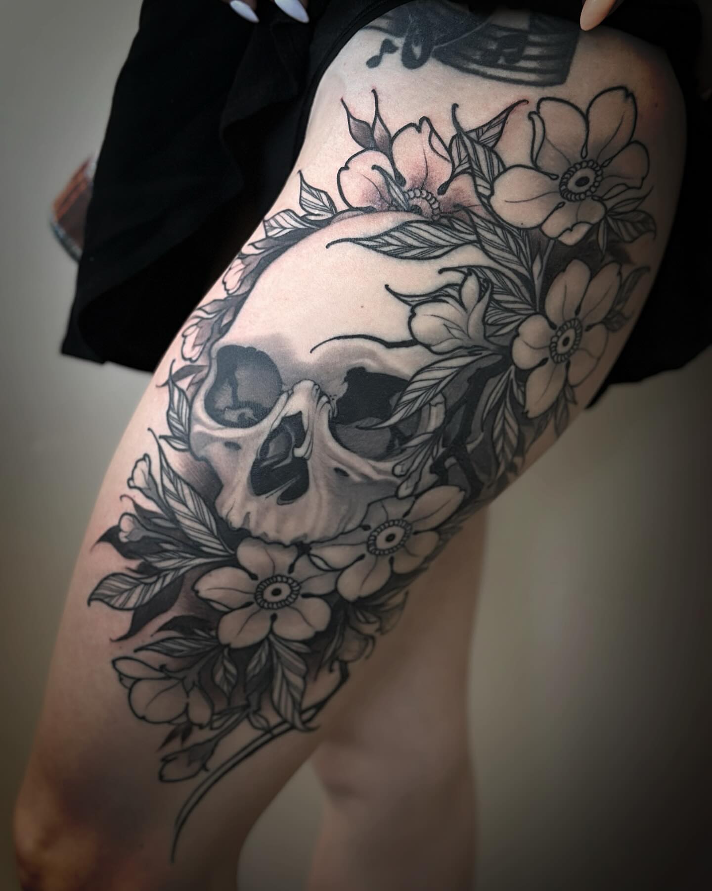 Skull and flowers black and grey tattoo on the thigh by Jeff Norton, Atascadero, California