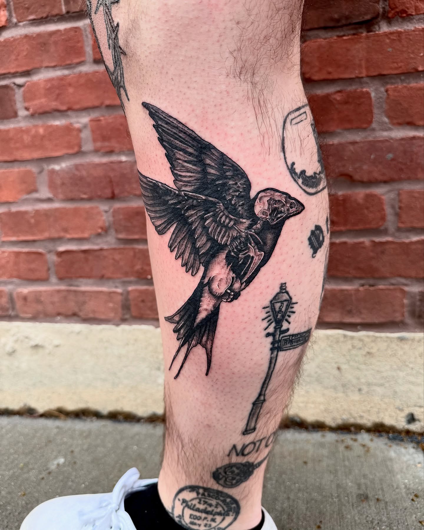 Swallow black and grey tattoo on the calf by Danielle