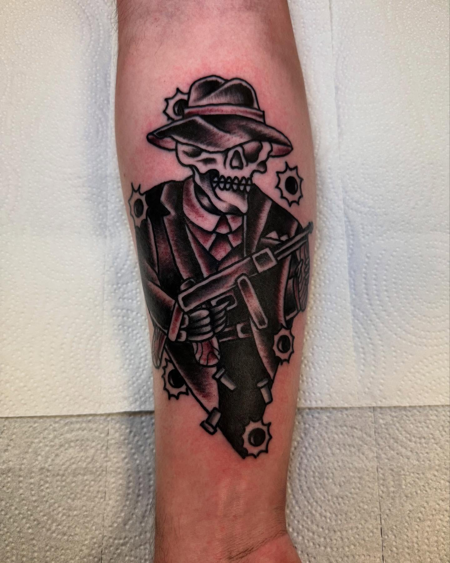 Skull with hat and gun American traditional tattoo on the forearm by Noah Diffenderfer, Phoenix, Arizona