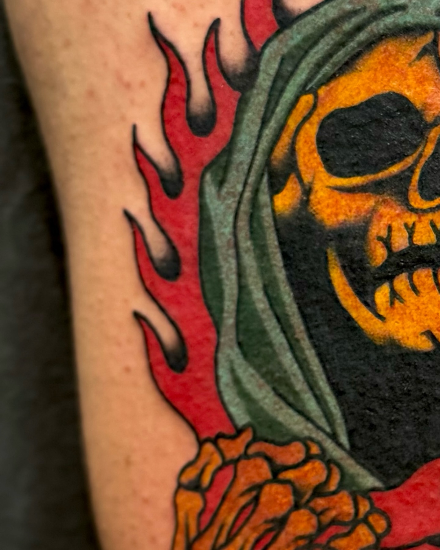 Flaming skull American traditional tattoo on the forearm by Ernie Rivera