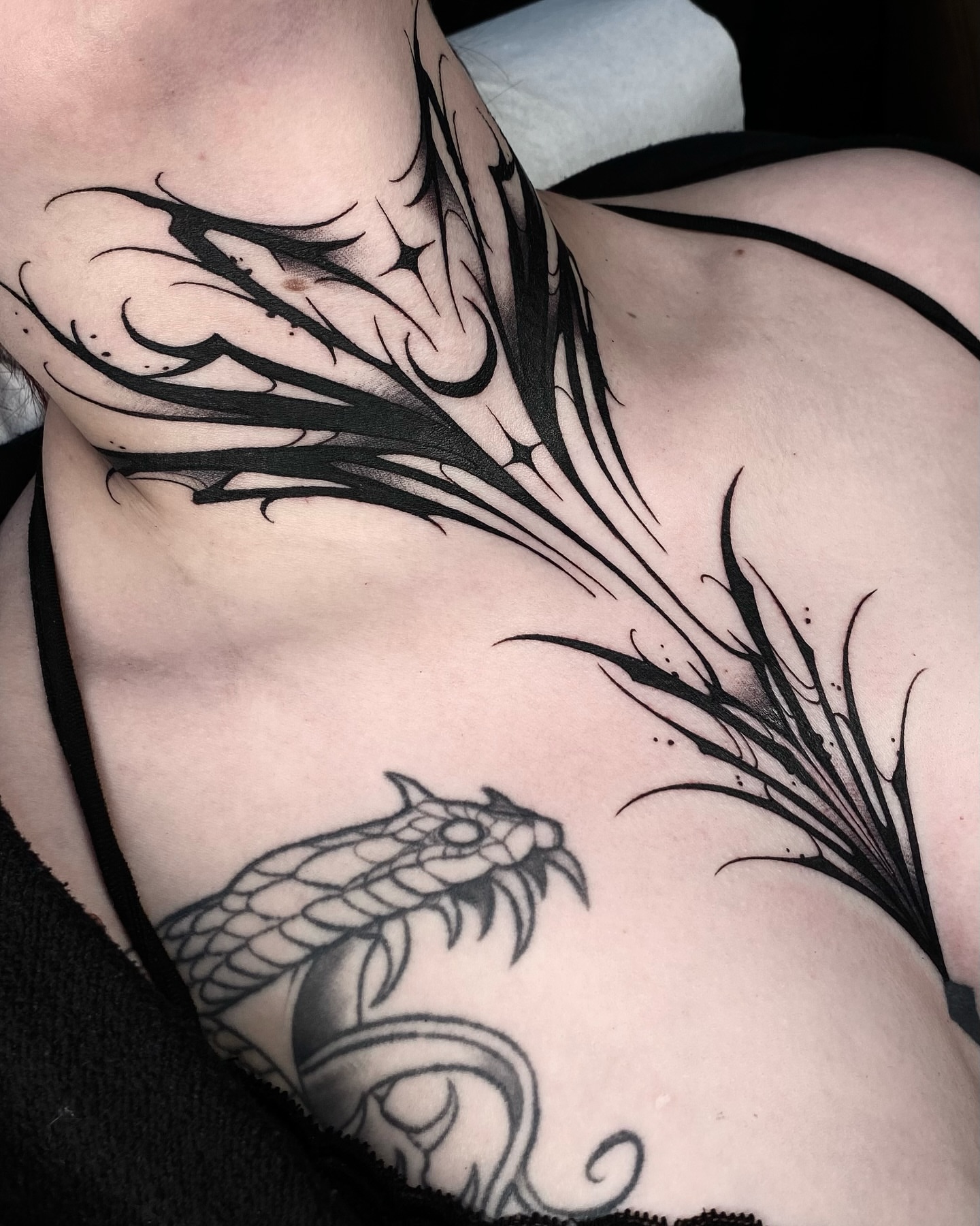 Feather and snake tribal tattoo on the chest by IVY