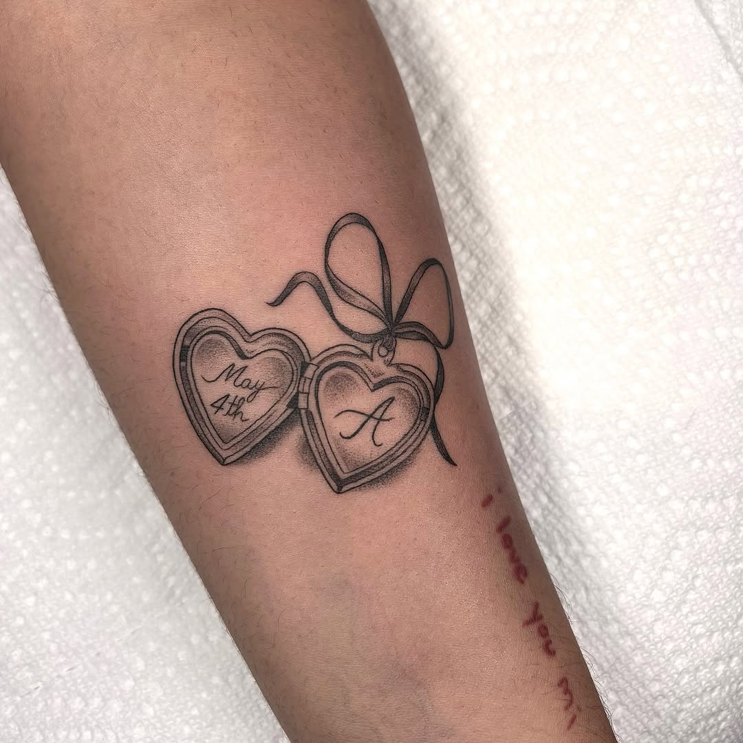 Heart locket with initials and date fine line tattoo on the forearm by Fineline tattoos by Kinsey