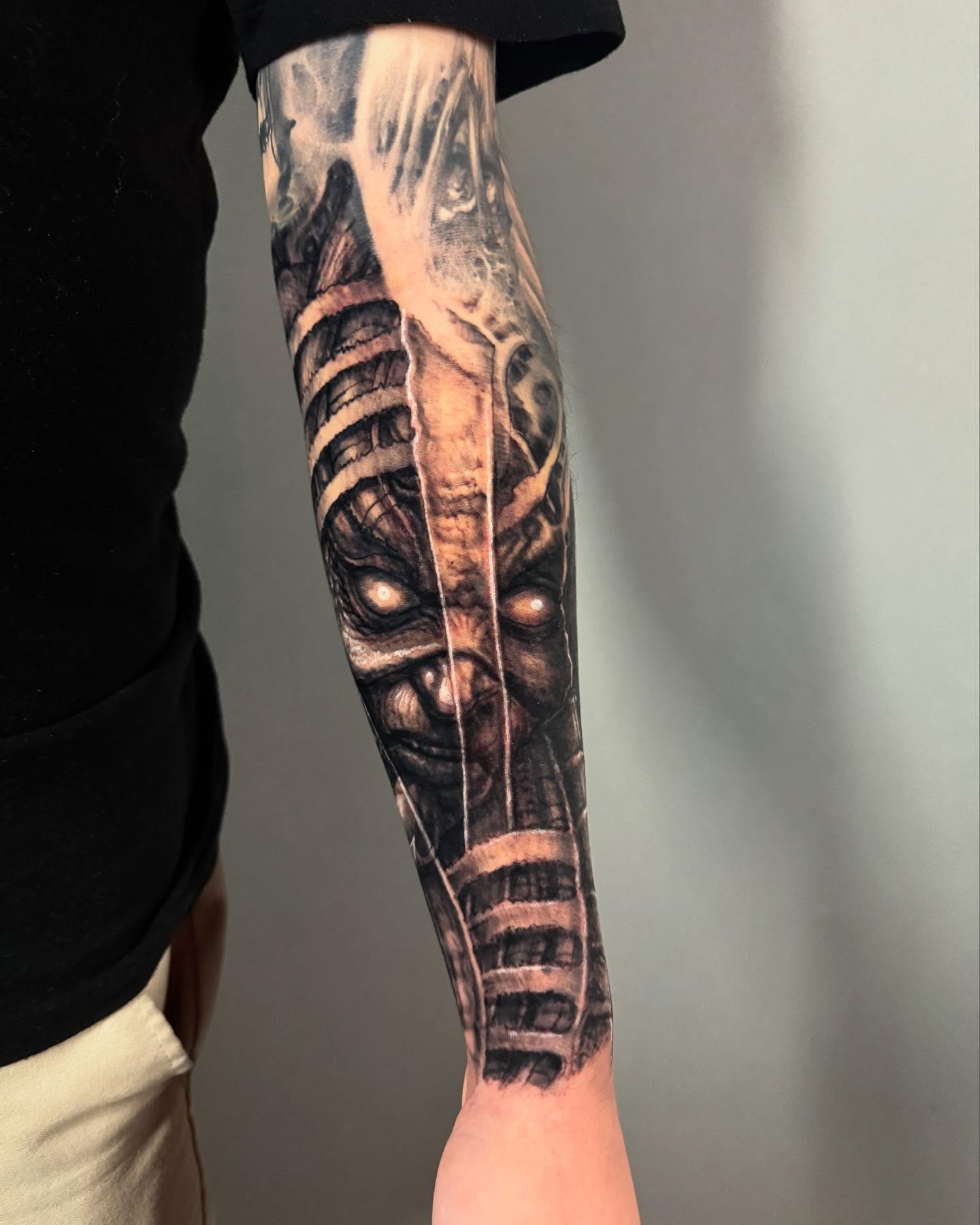 Cyborg face realism tattoo on the forearm by Paul Booth