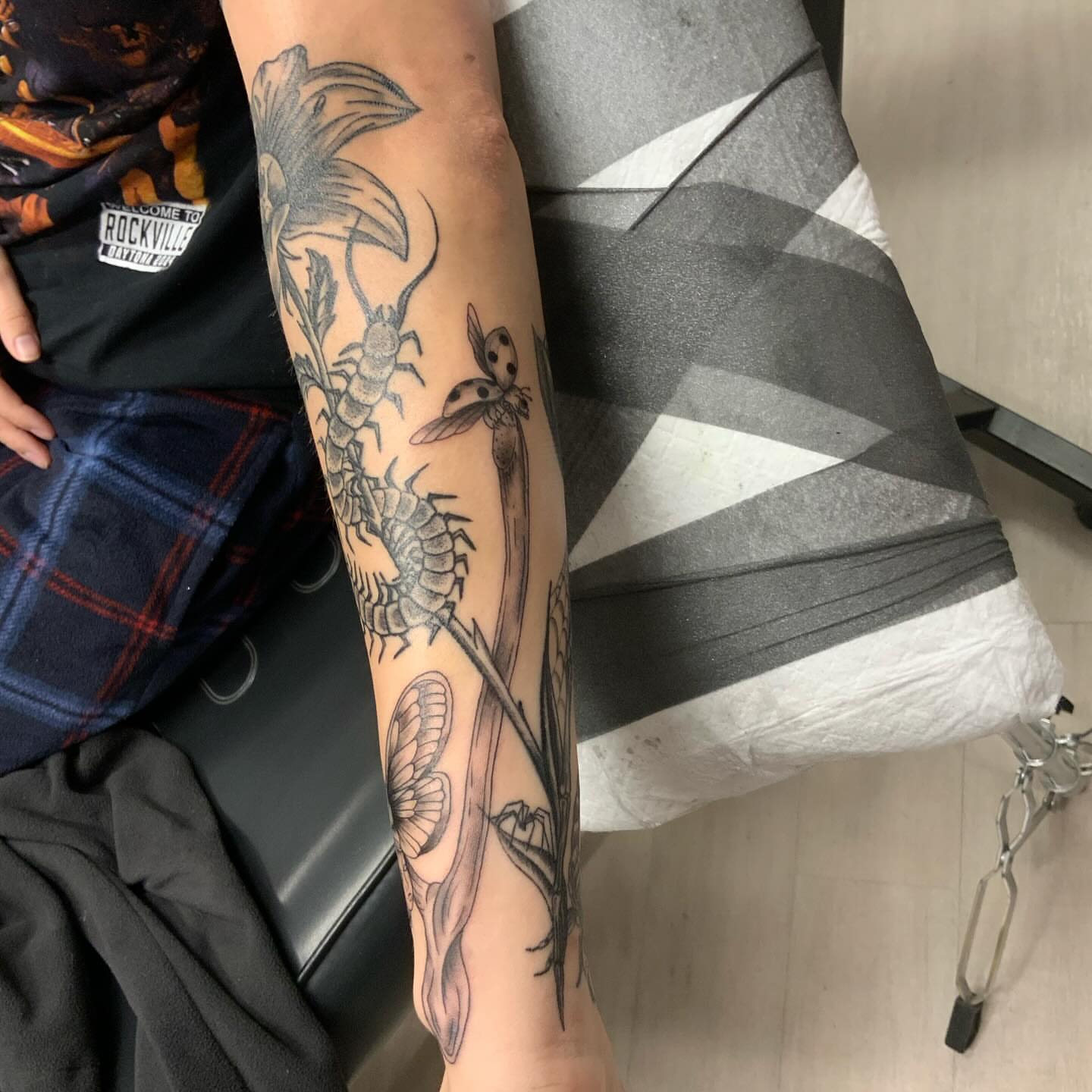Insects and flowers black and grey tattoo on the forearm by QUEEN TATTOO Stephanie Larson
