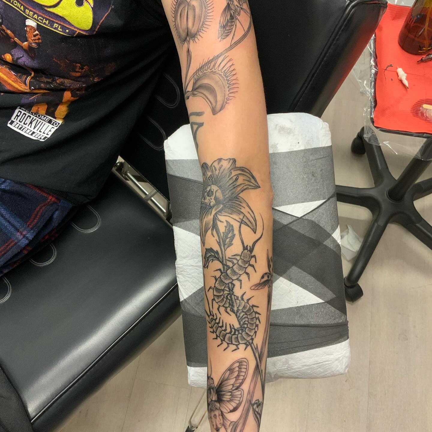 Insect and flower black and grey tattoo on the forearm by QUEEN TATTOO Stephanie Larson