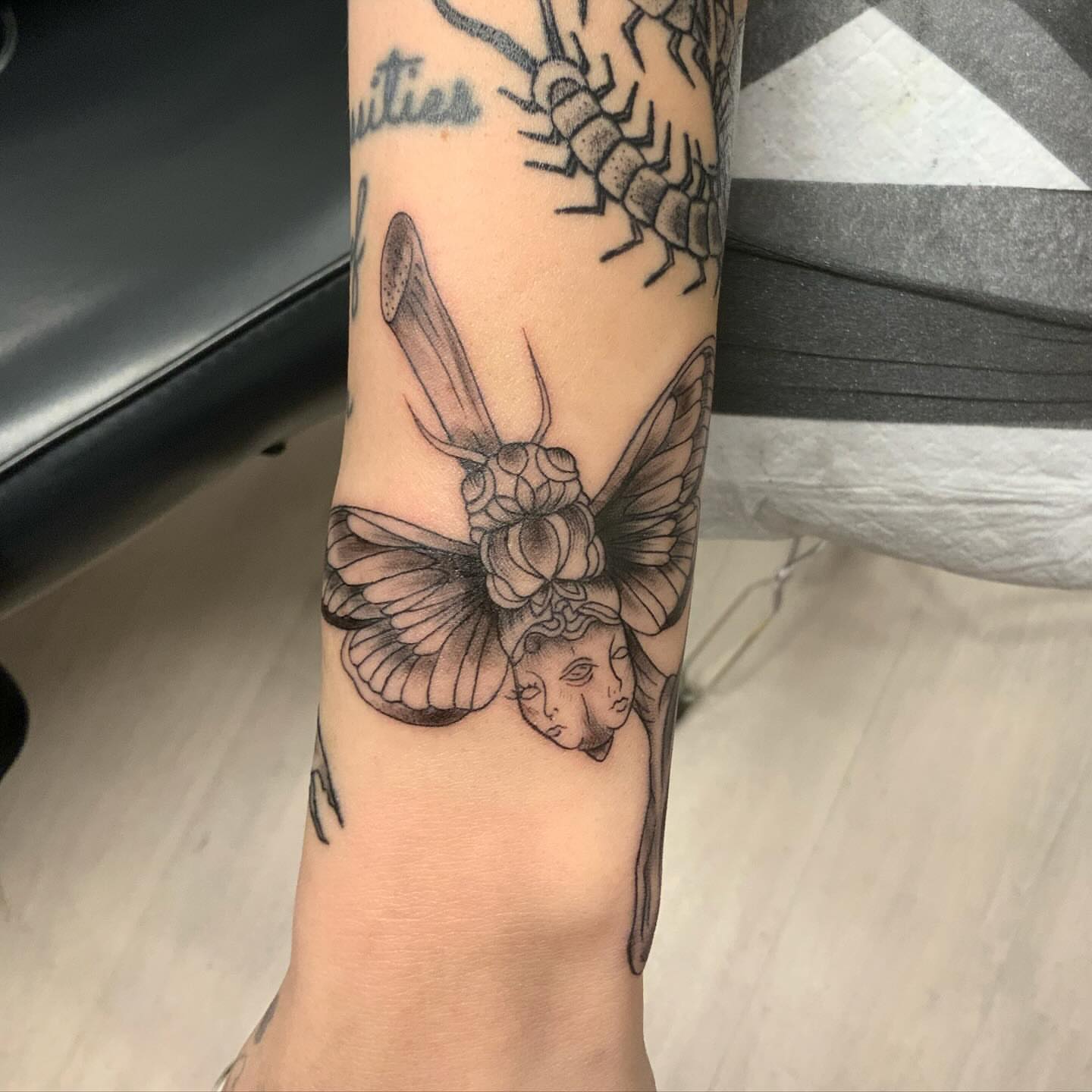 Moth with faces realism tattoo on the forearm by QUEEN TATTOO Stephanie Larson