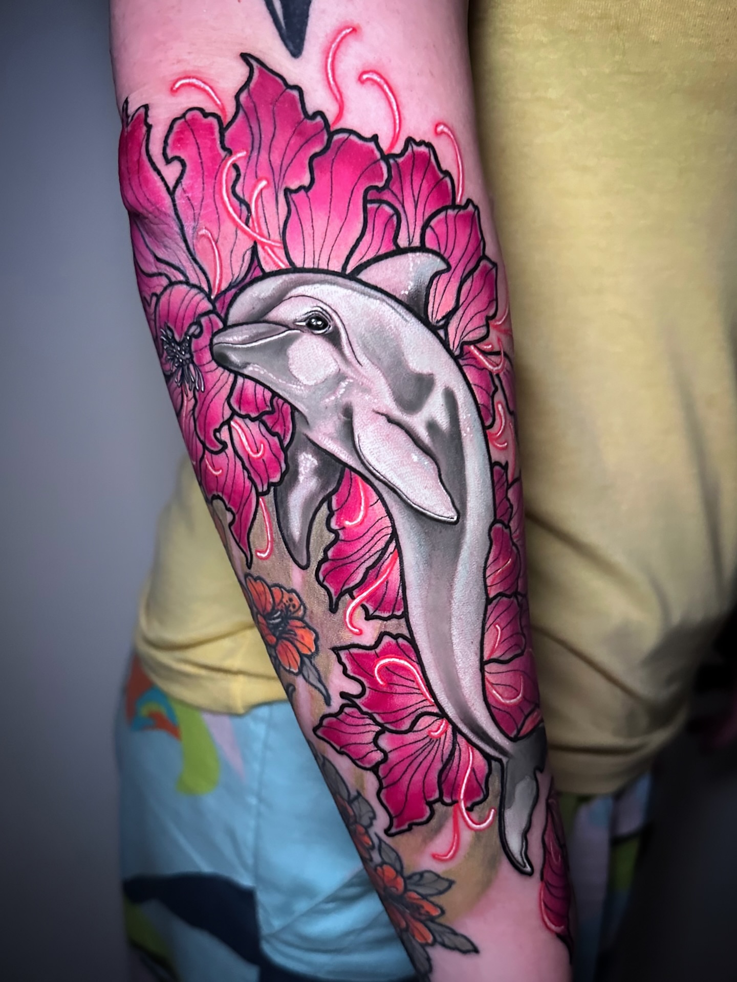 Dolphin and flowers new school tattoo on the forearm by Naysla Droguett