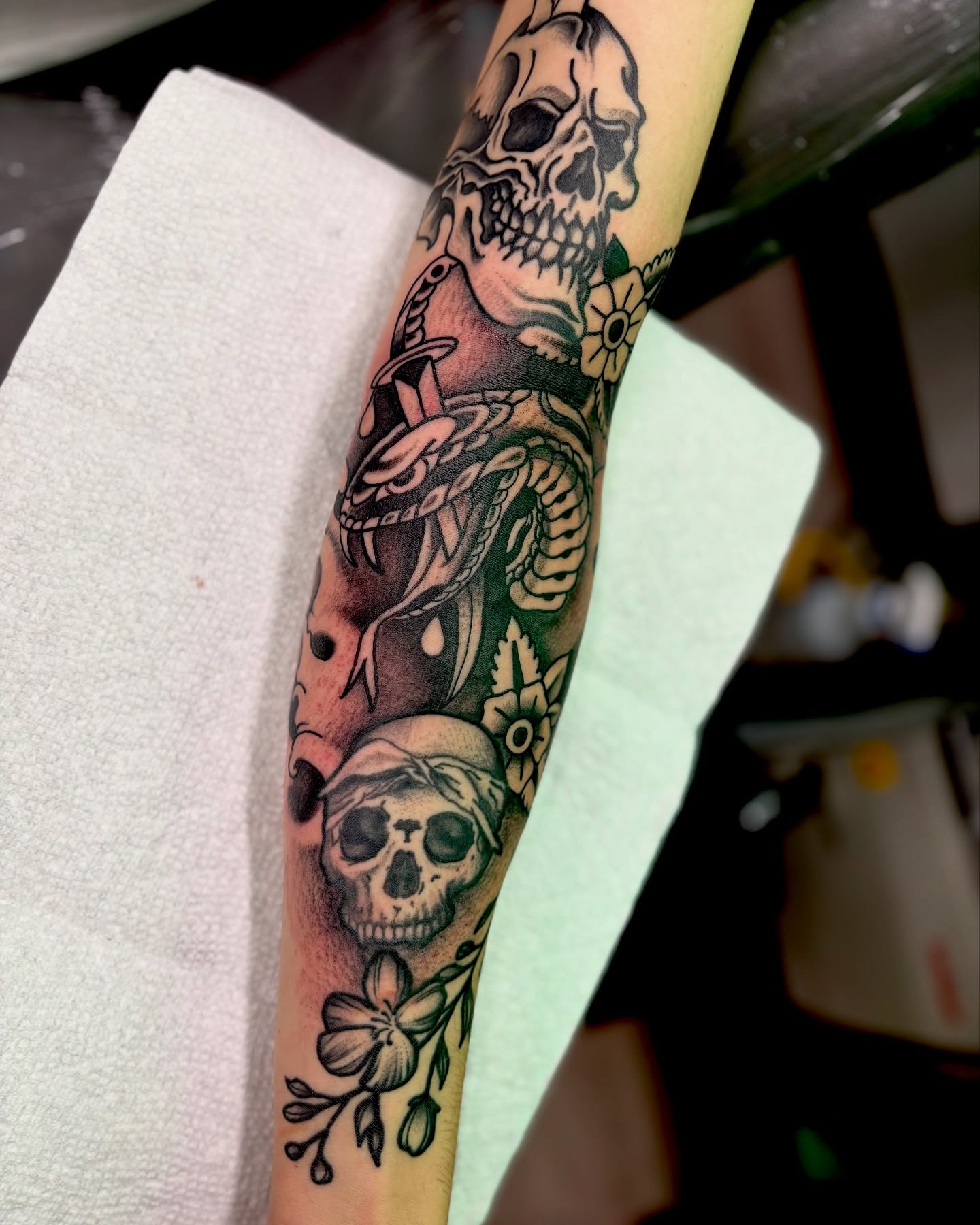 Skulls and flowers American traditional tattoo on the forearm by Ogden Tattoo Parlor